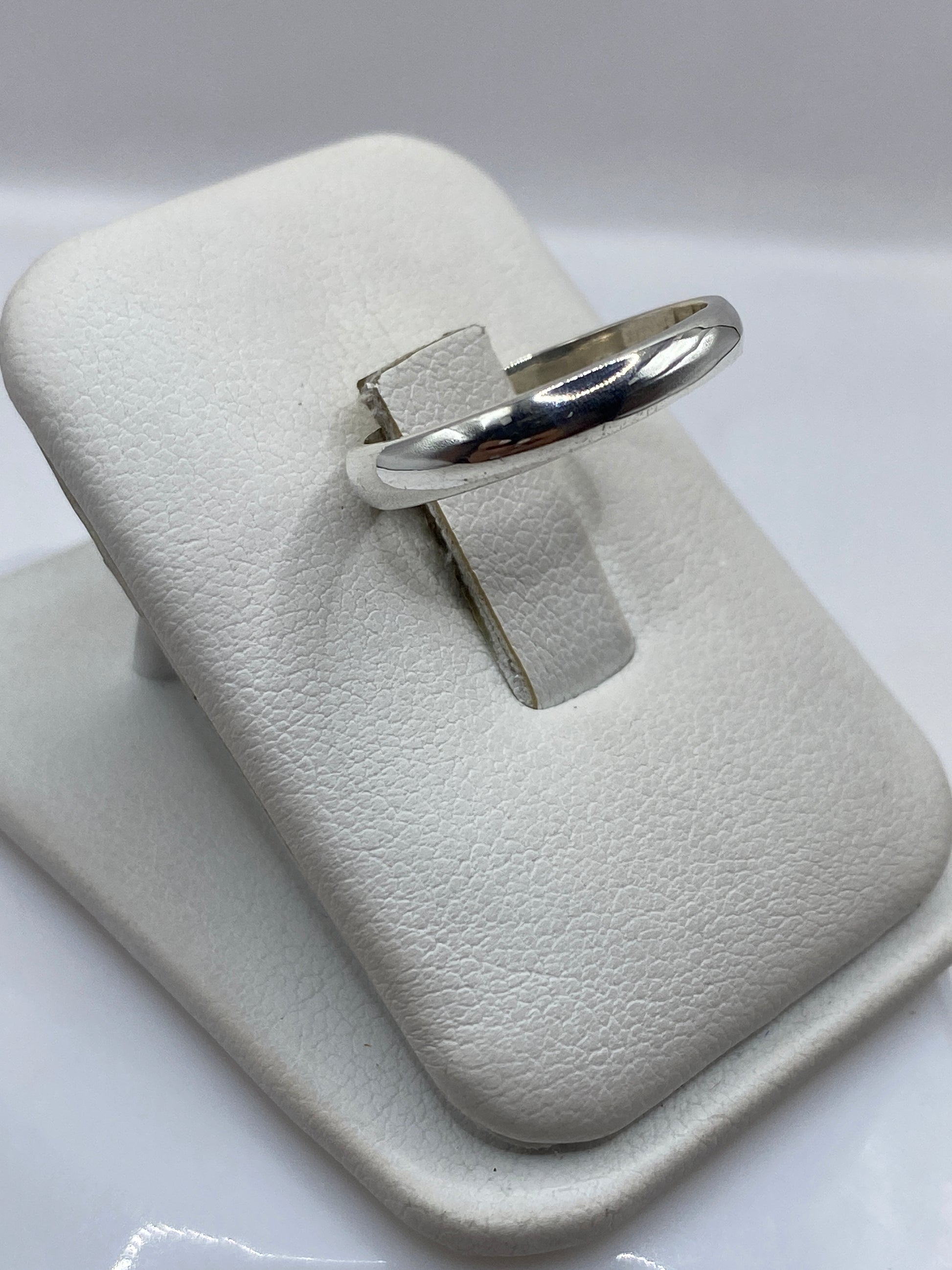 Anillo minimalista de plata en la mano, mostrando brillo espejo