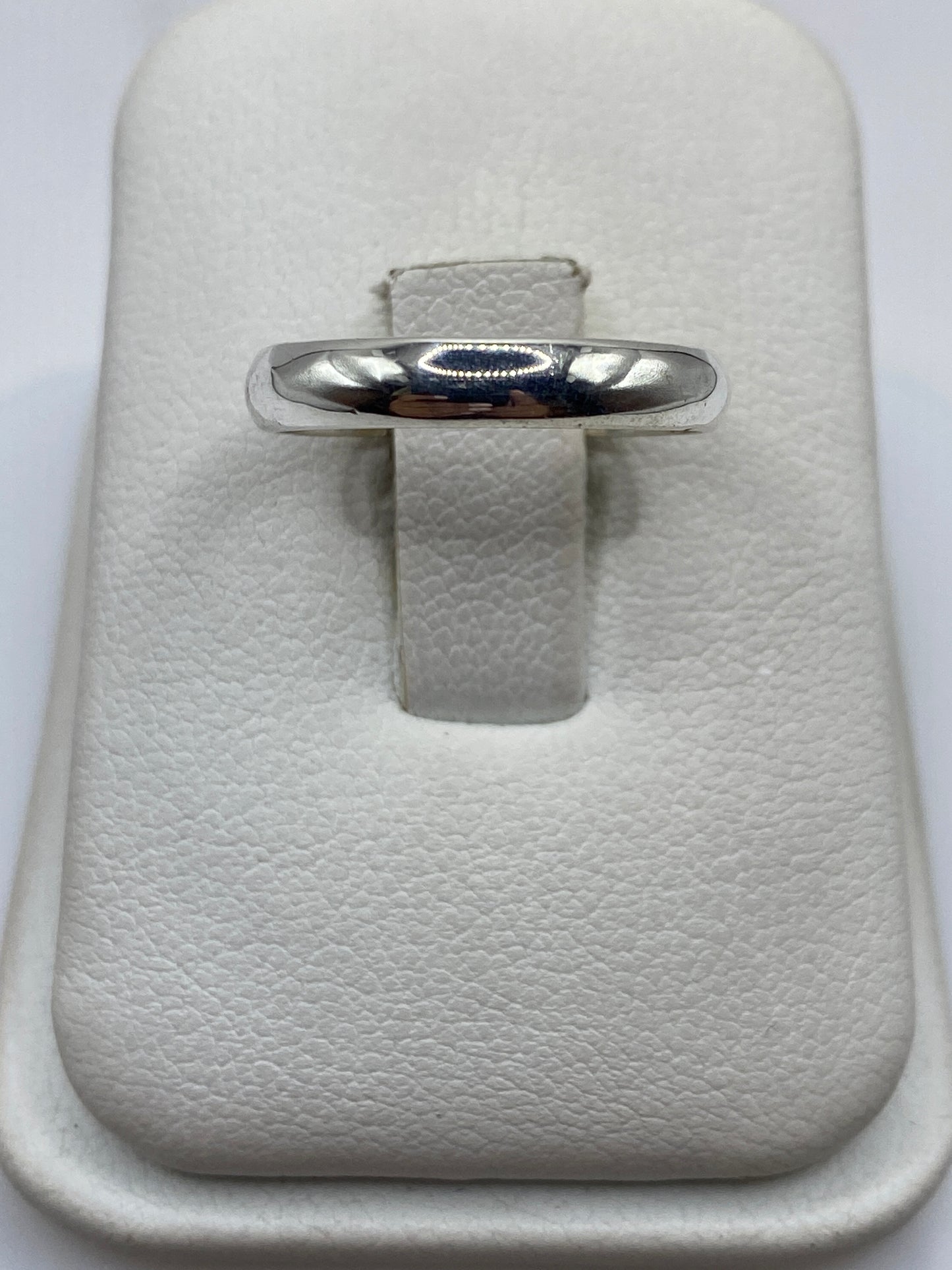 Anillo de plata banda pulida minimalista en estuche blanco, frente