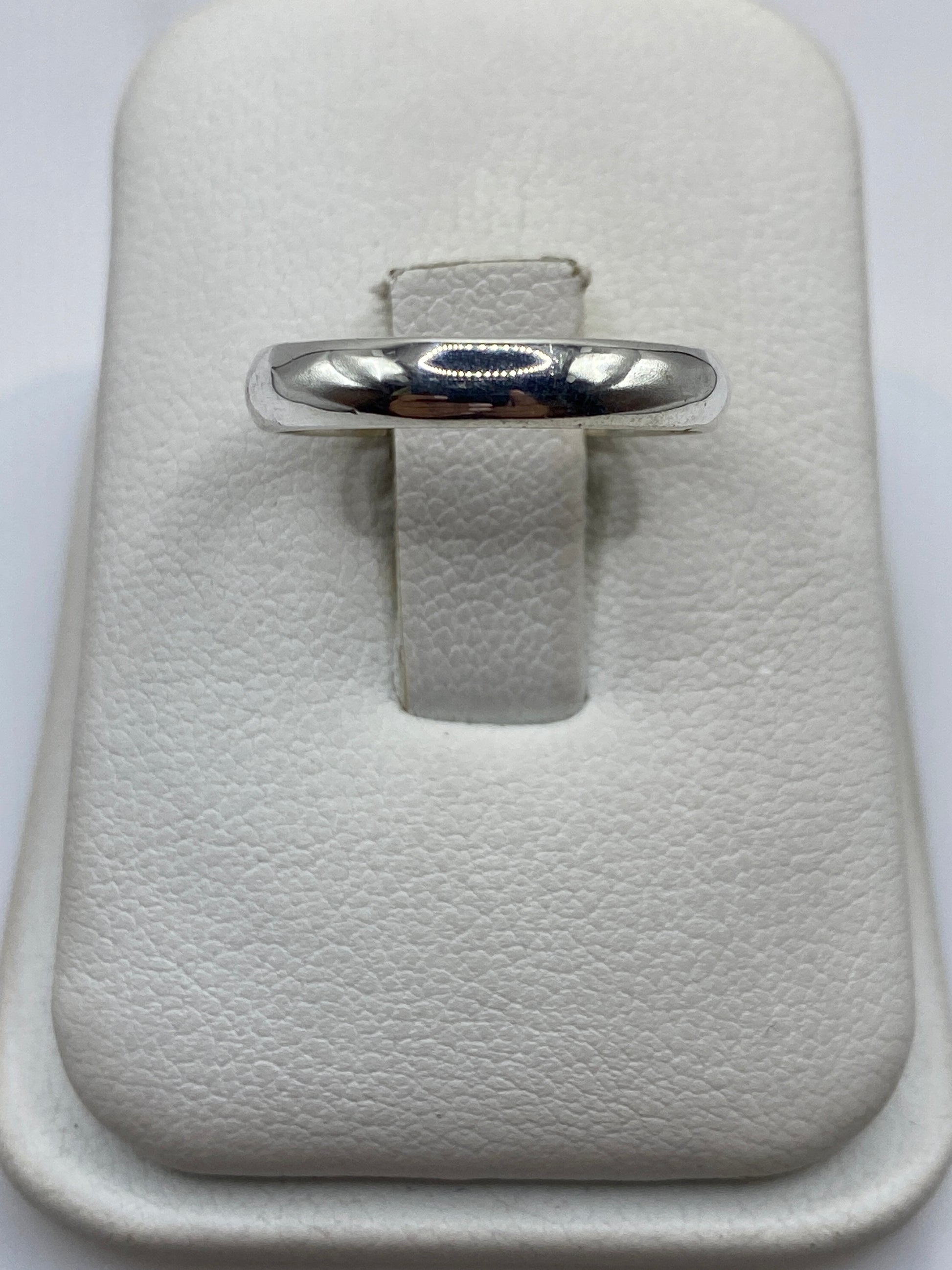 Anillo de plata banda pulida minimalista en estuche blanco, frente