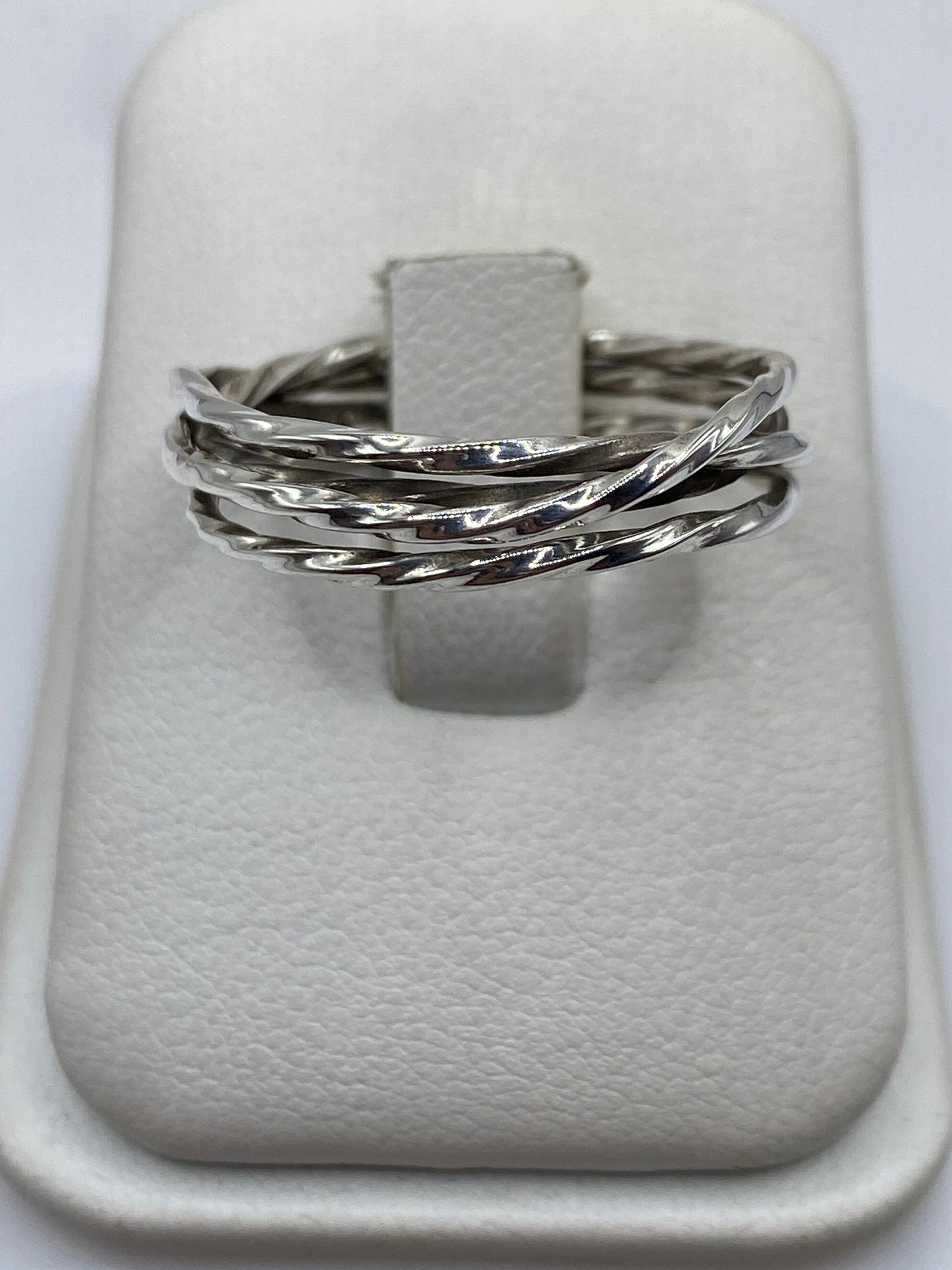 Anillo de plata eslabones entrelazados en exhibidor blanco, vista frontal