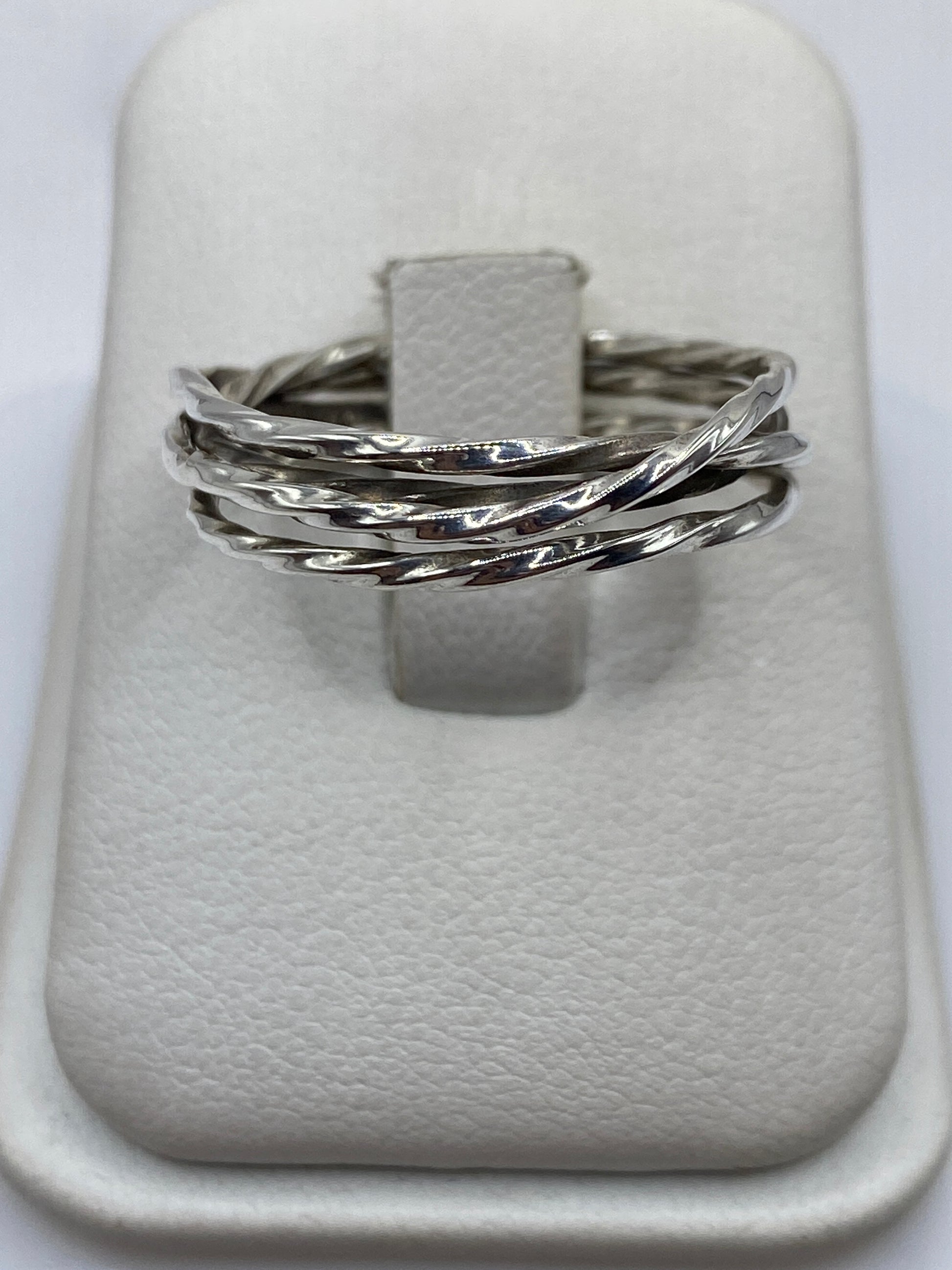 Anillo de plata eslabones entrelazados en exhibidor blanco, vista frontal