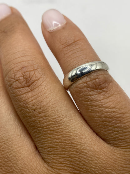 Anillo sencillo de plata sobre fondo gris, detalle del acabado brillante