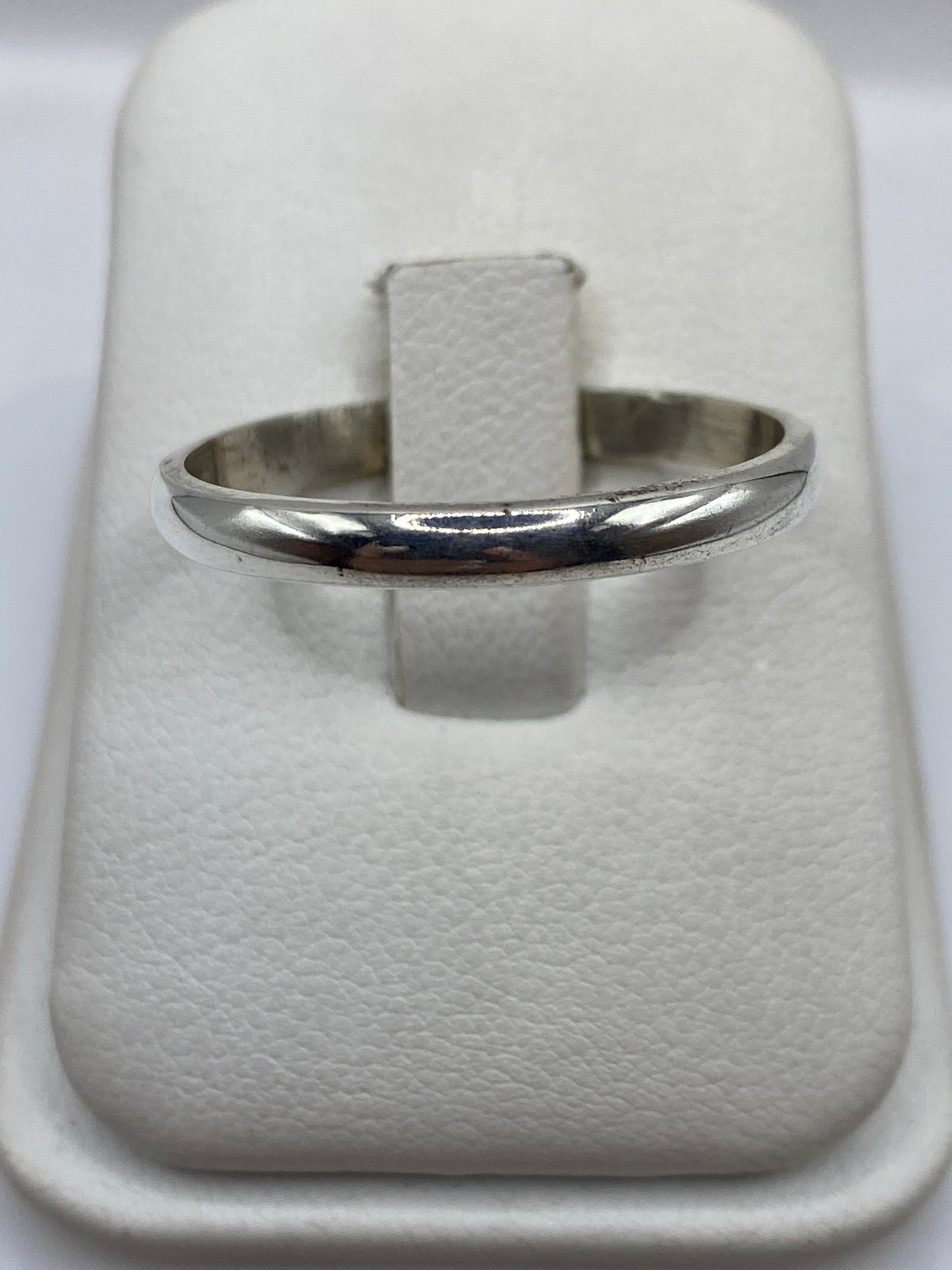 Anillo de plata banda lisa pulida en dedo, vista frontal minimalista