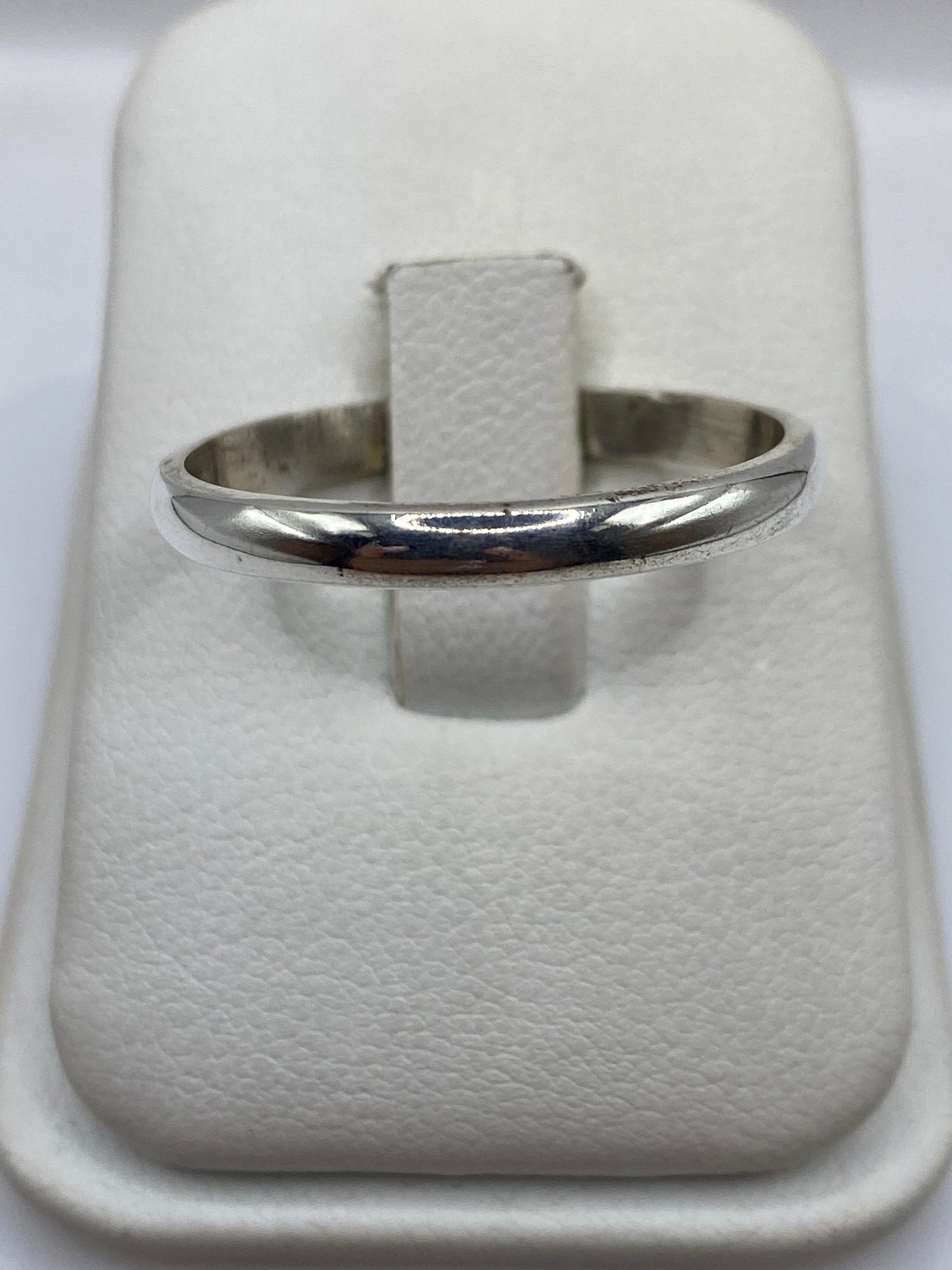 Anillo de plata banda lisa pulida en dedo, vista frontal minimalista