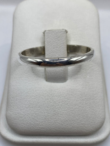 Anillo de plata banda lisa pulida en dedo, vista frontal minimalista