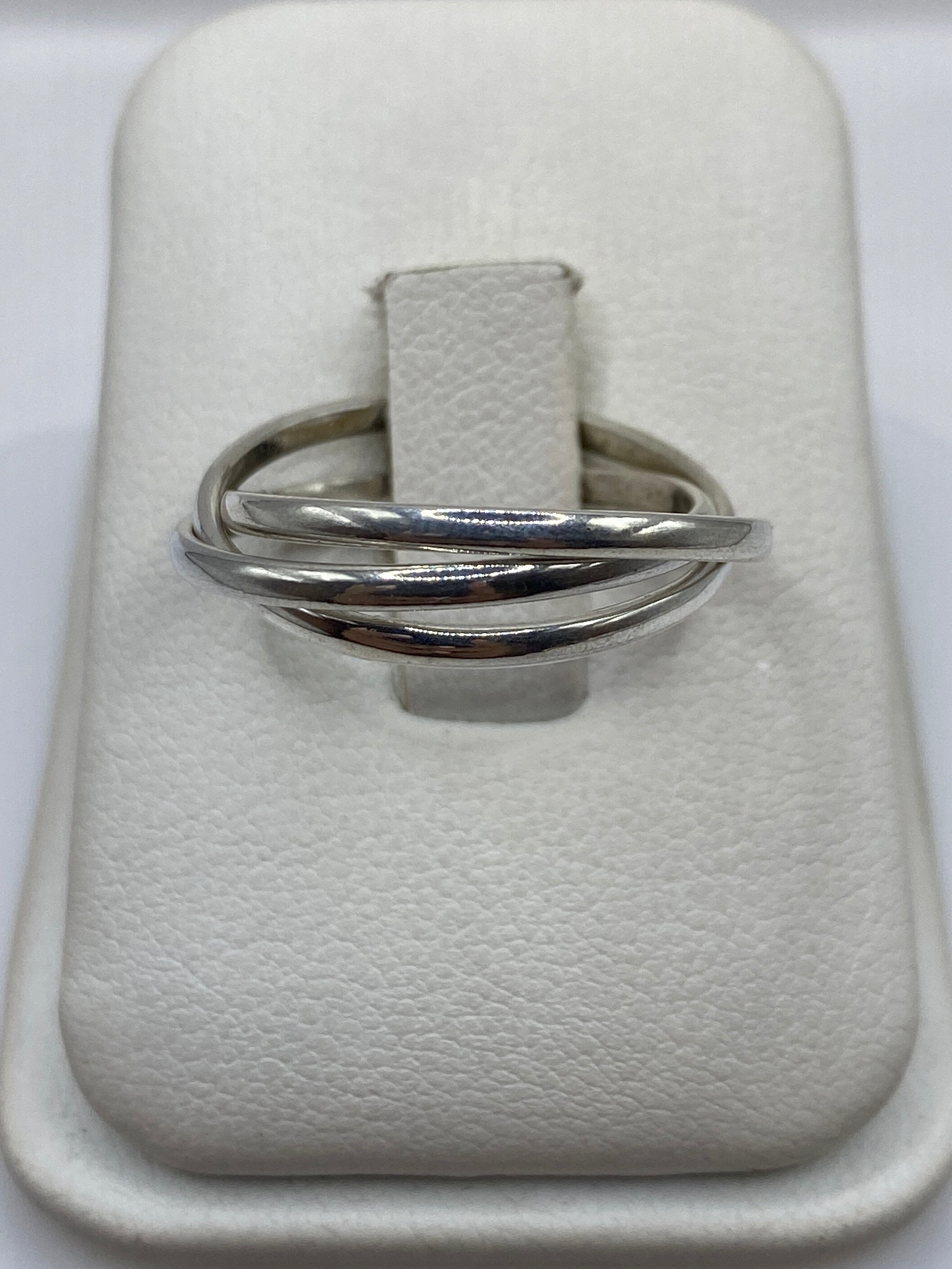Anillo de plata con tres bandas cruzadas en la mano de una mujer