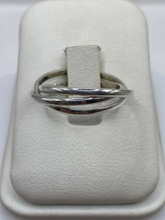 Anillo de plata con tres bandas cruzadas en la mano de una mujer