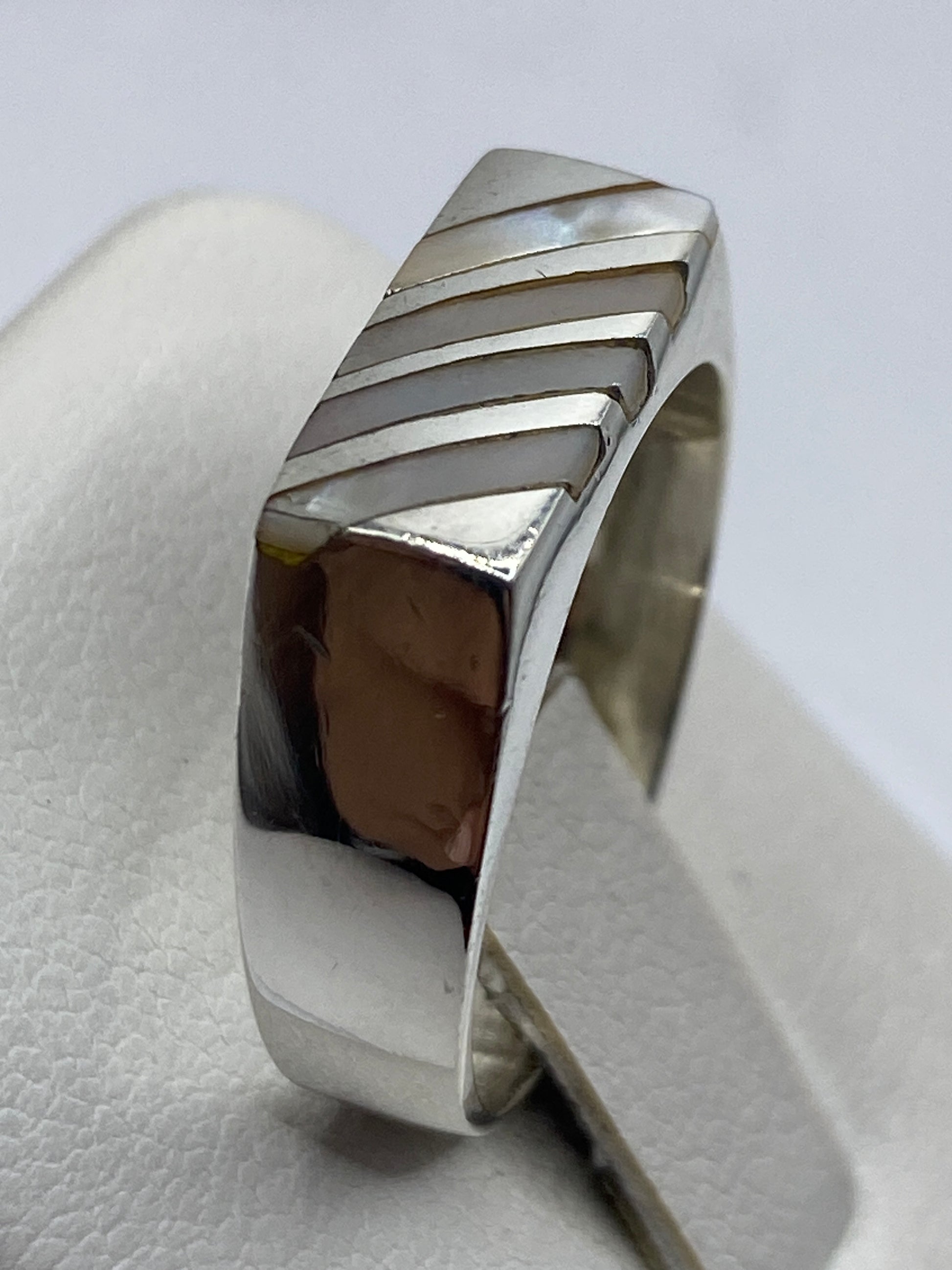 Anillo de plata con perla blanca puesto en la mano de un hombre adulto
