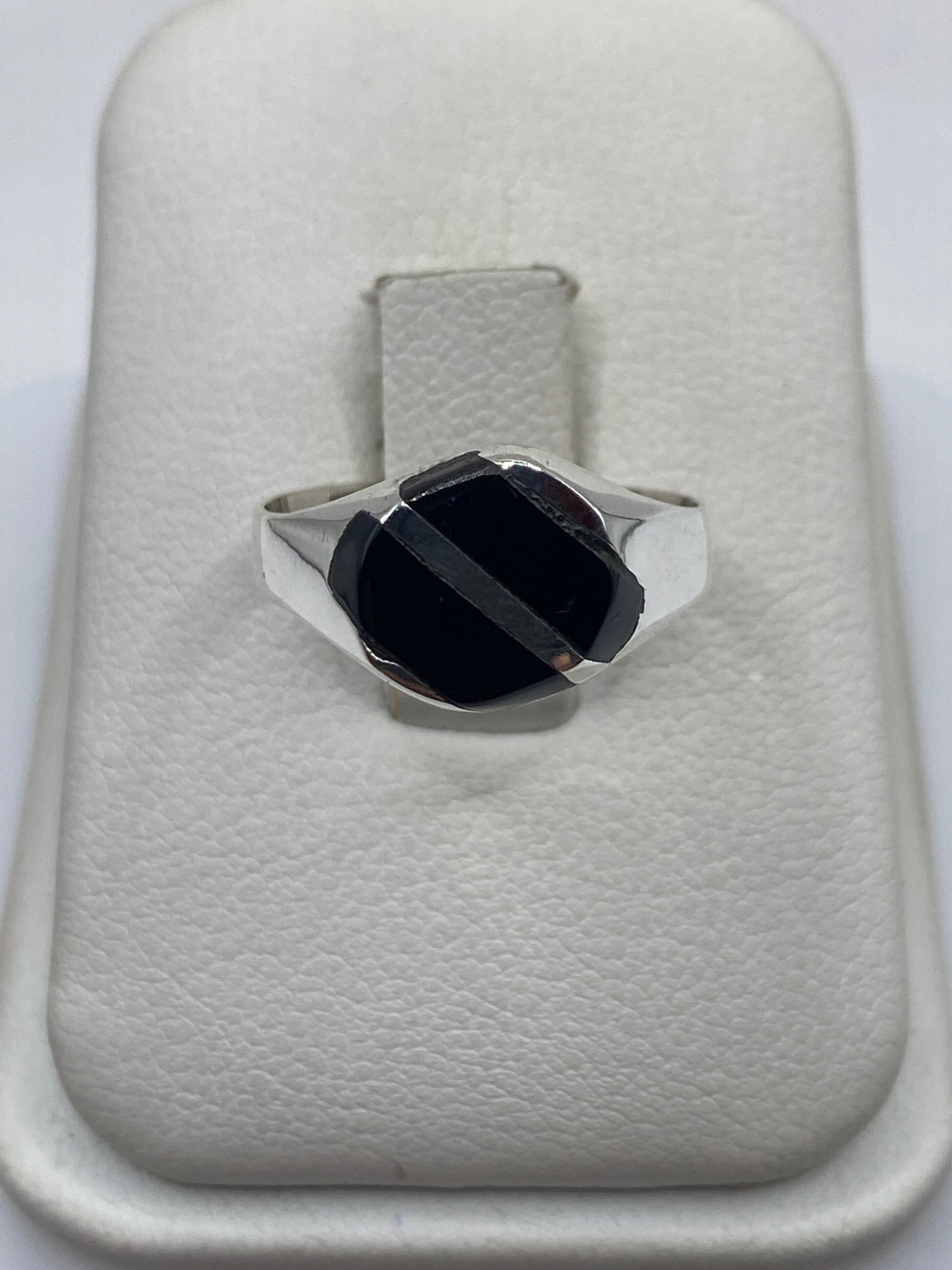 Anillo de plata con ónix negro en forma de solitario moderno sobre base de piel blanca