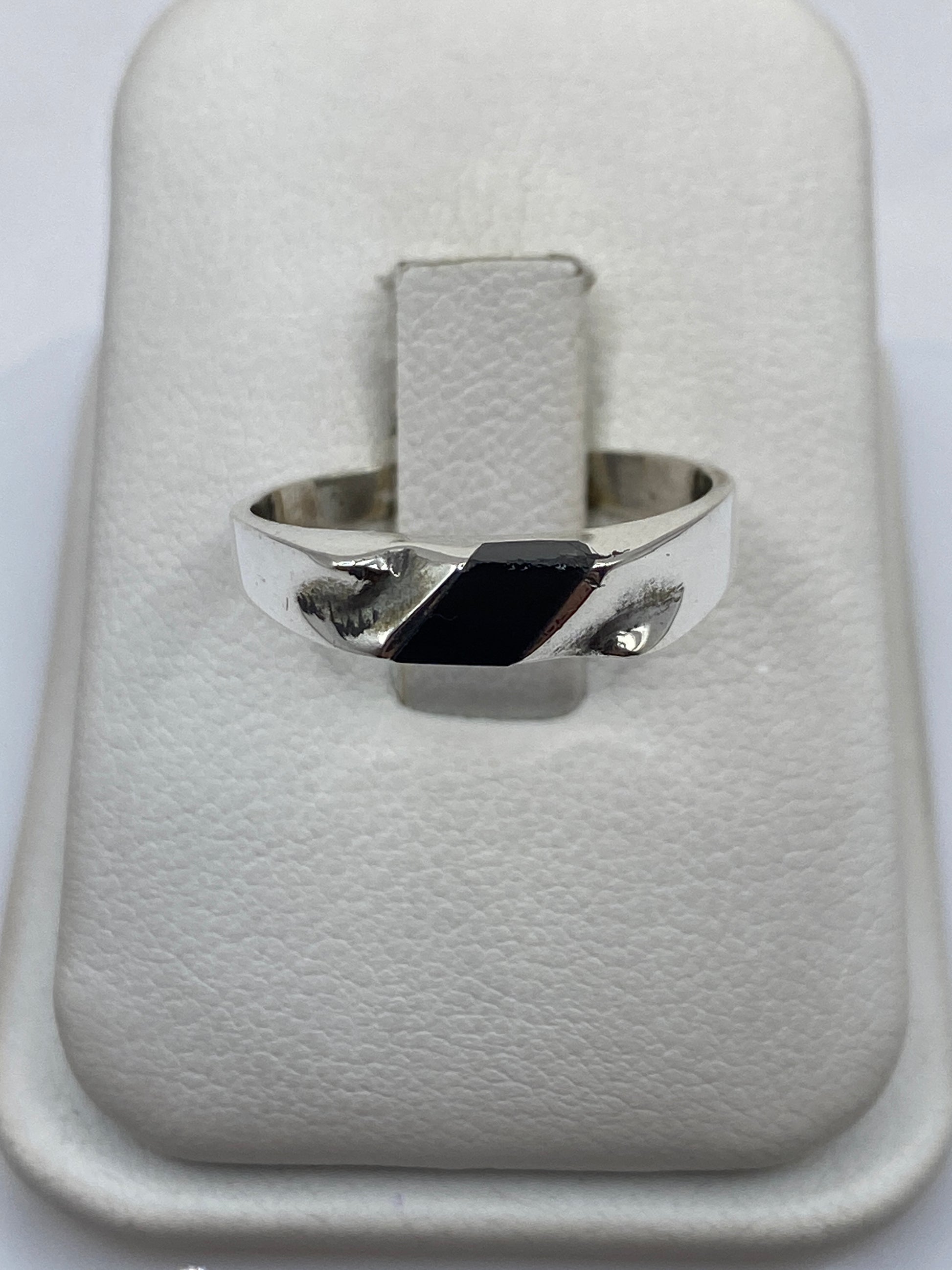 Anillo de plata .925 con ónix negro rectangular en mano de persona con piel clara