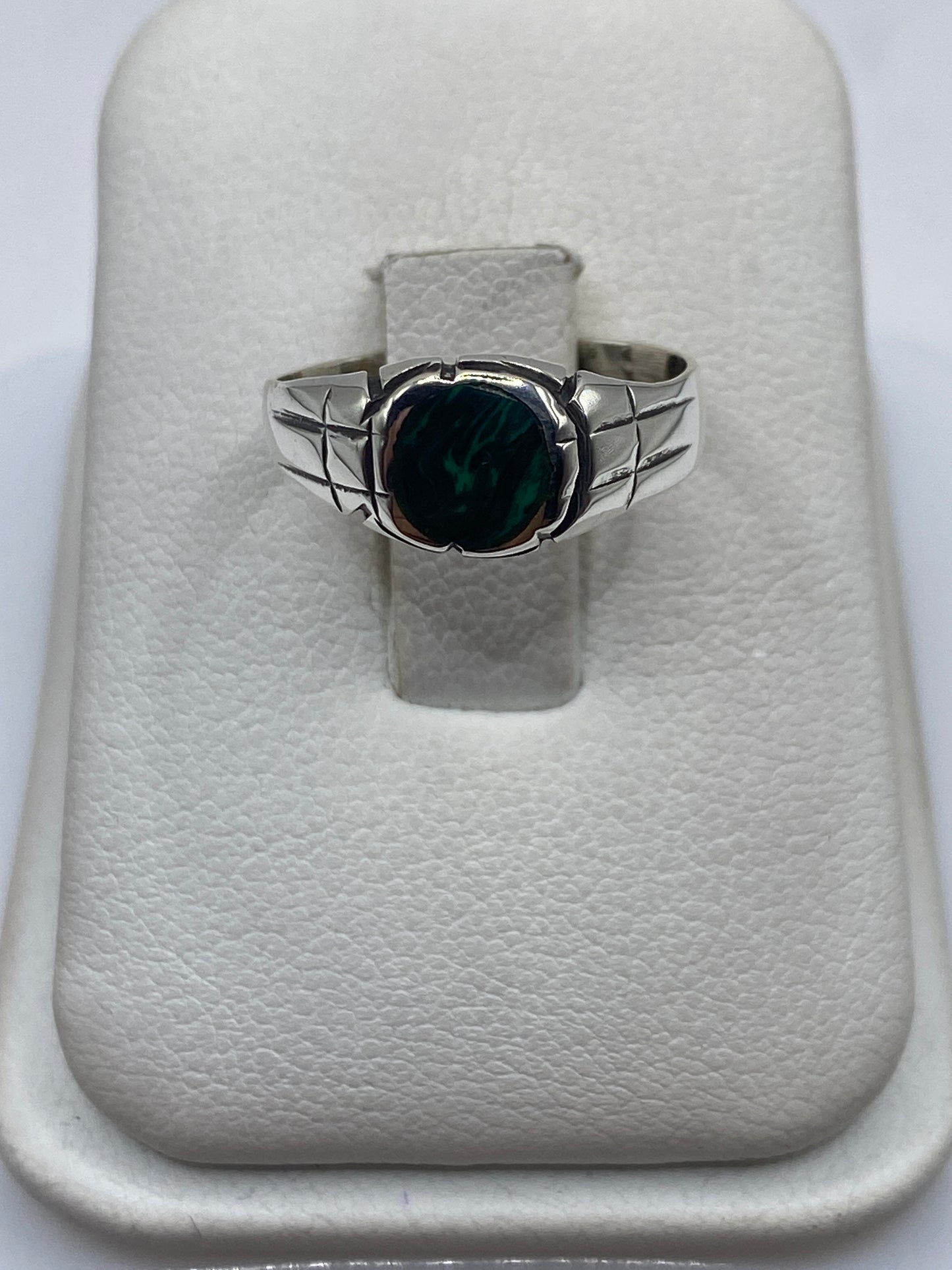Anillo de plata con malaquita verde en dedo de mujer sobre fondo blanco