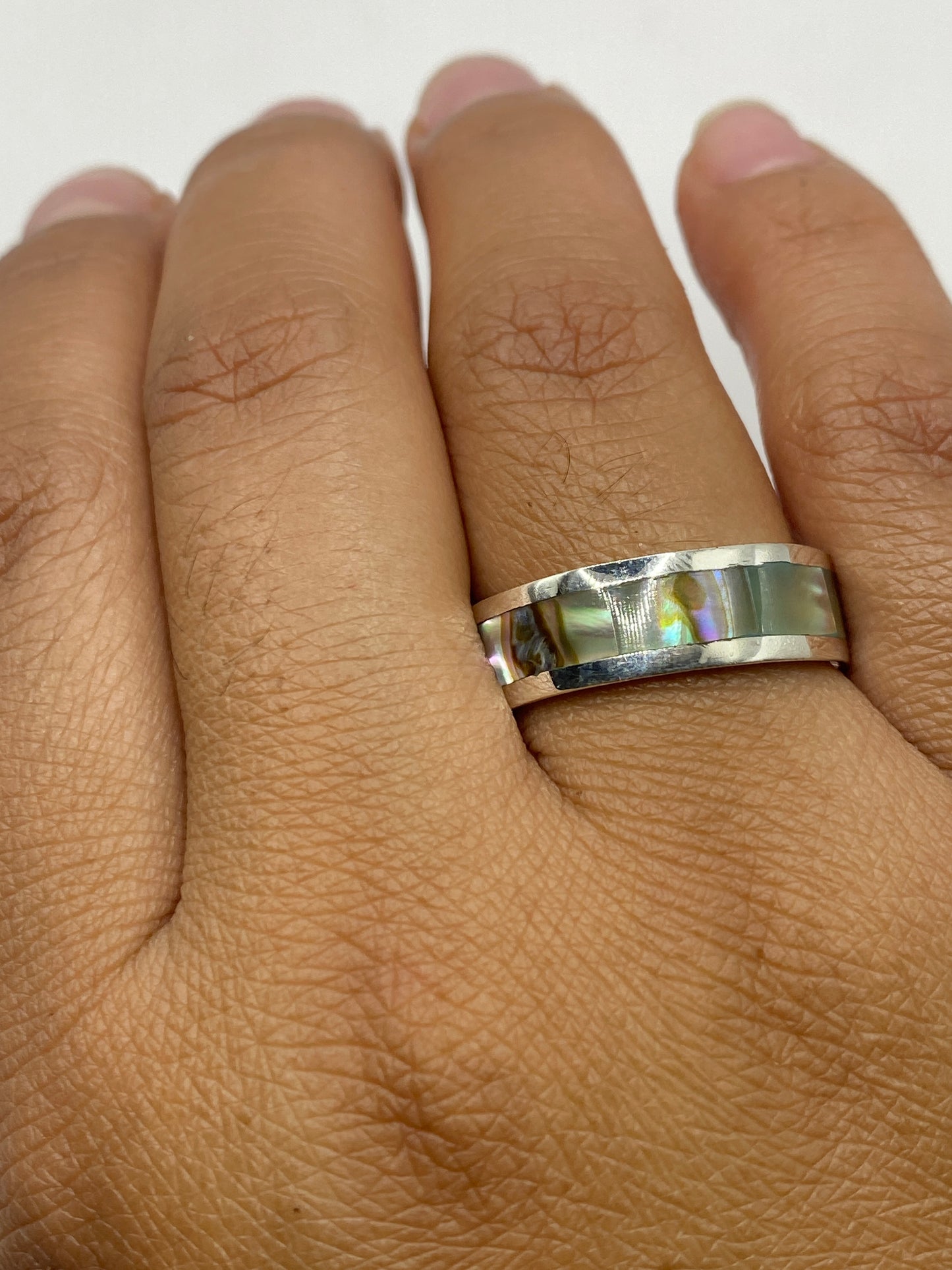 Anillo sobre fondo blanco con luz natural revelando el acabado pulido y el sello MEXICO