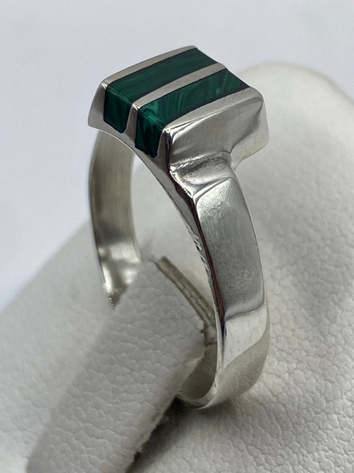 Anillo de plata con malaquita puesto en mano, vista lateral