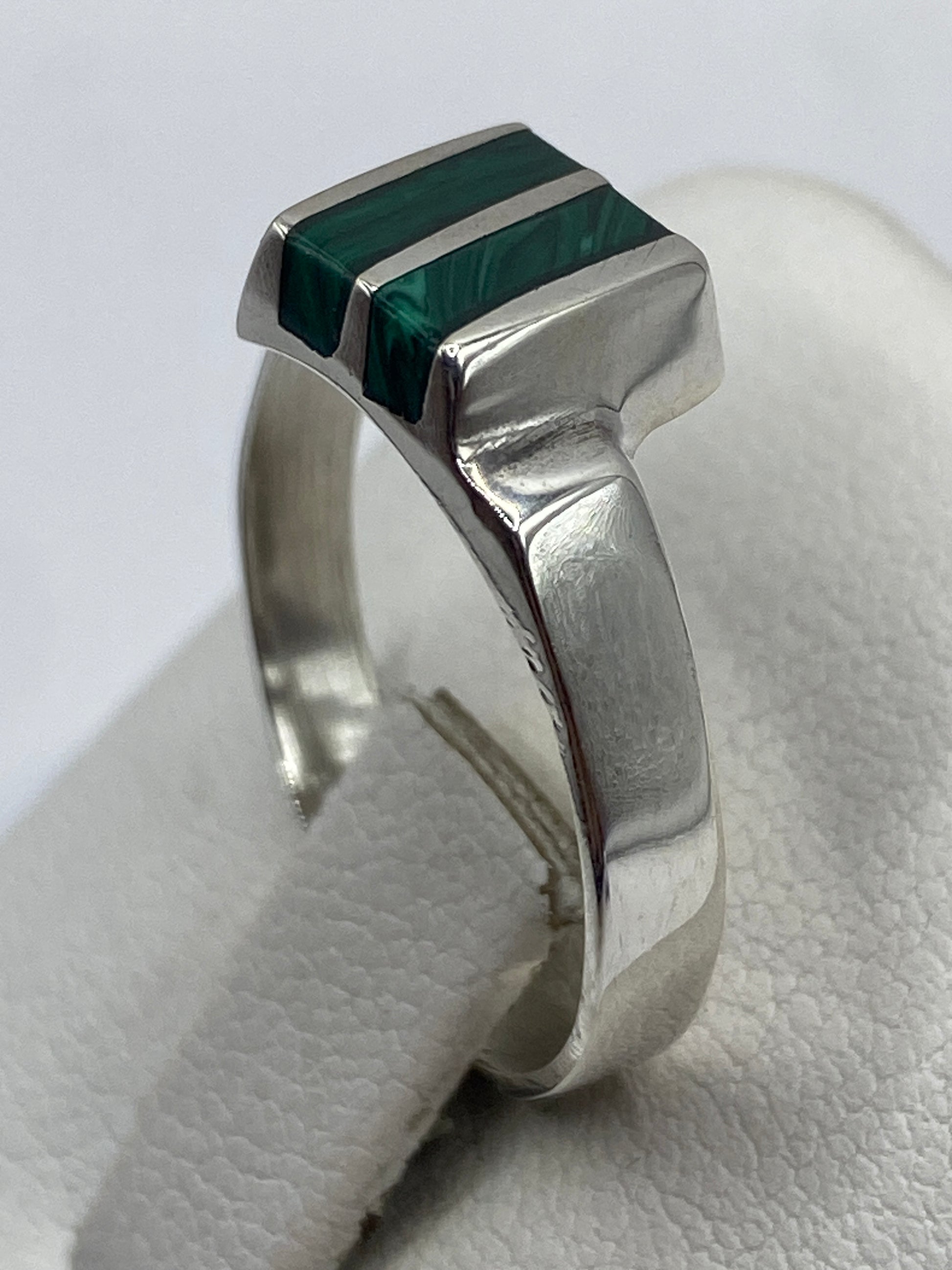 Anillo de plata con malaquita puesto en mano, vista lateral
