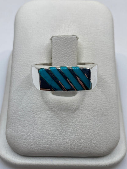 Anillo de plata con turquesa azul cielo en diseño geométrico en diagonal, visto desde arriba en estuche blanco