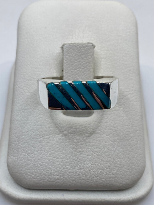 Anillo de plata con turquesa azul cielo en diseño geométrico en diagonal, visto desde arriba en estuche blanco