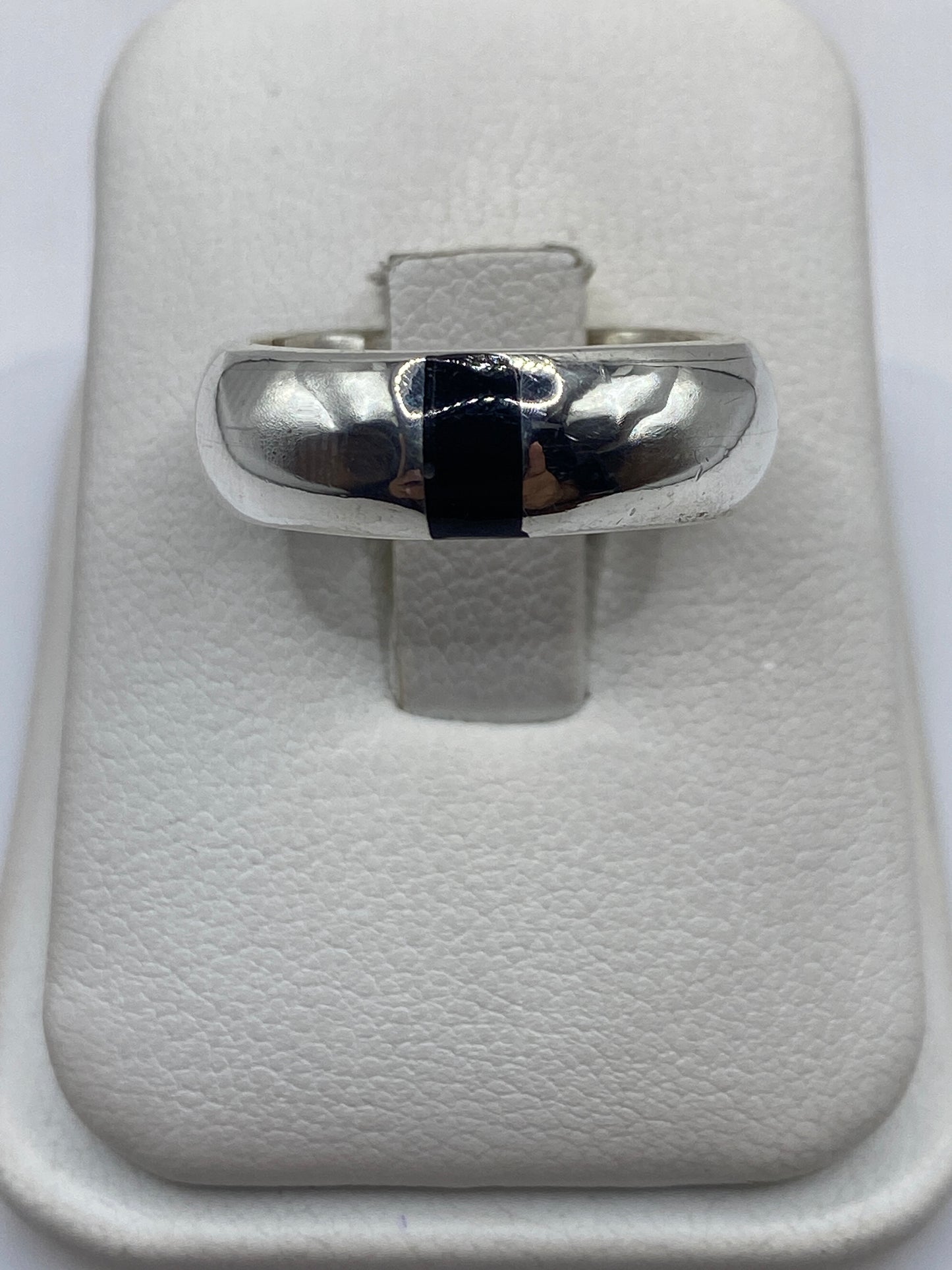 Anillo de plata con ónix negro pulido, banda ancha, en dedo de hombre