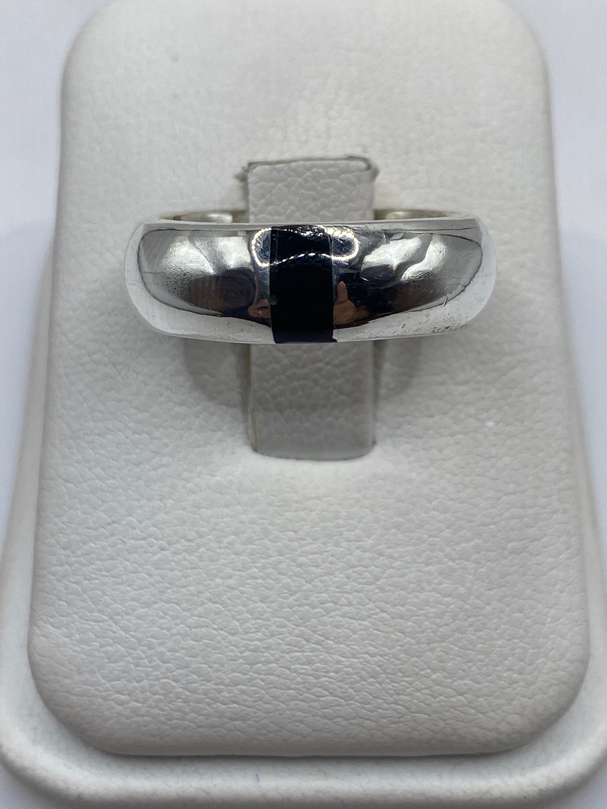 Anillo de plata con ónix negro pulido, banda ancha, en dedo de hombre
