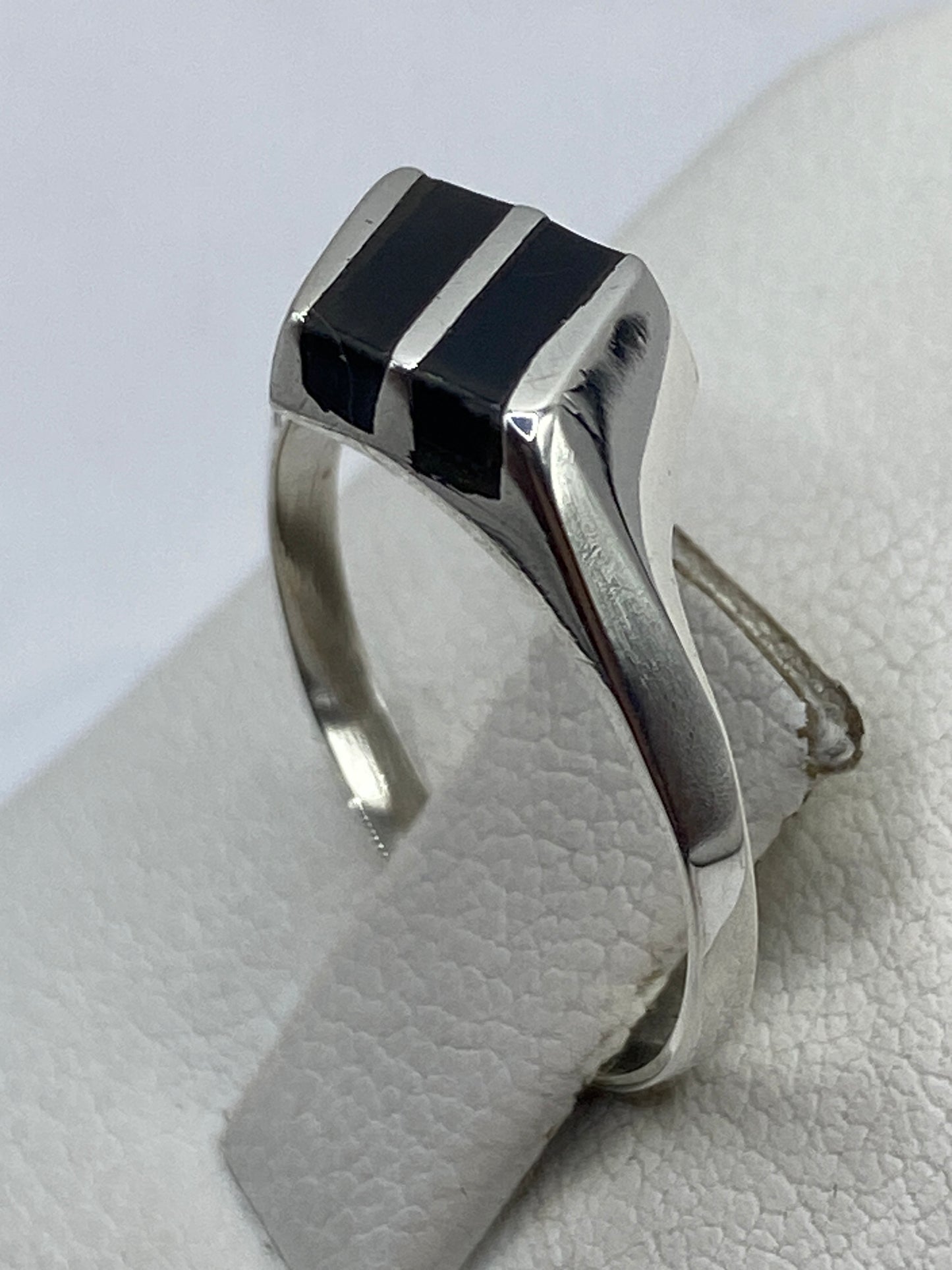 Detalle del anillo en la mano mostrando el acabado pulido del ónix y la plata