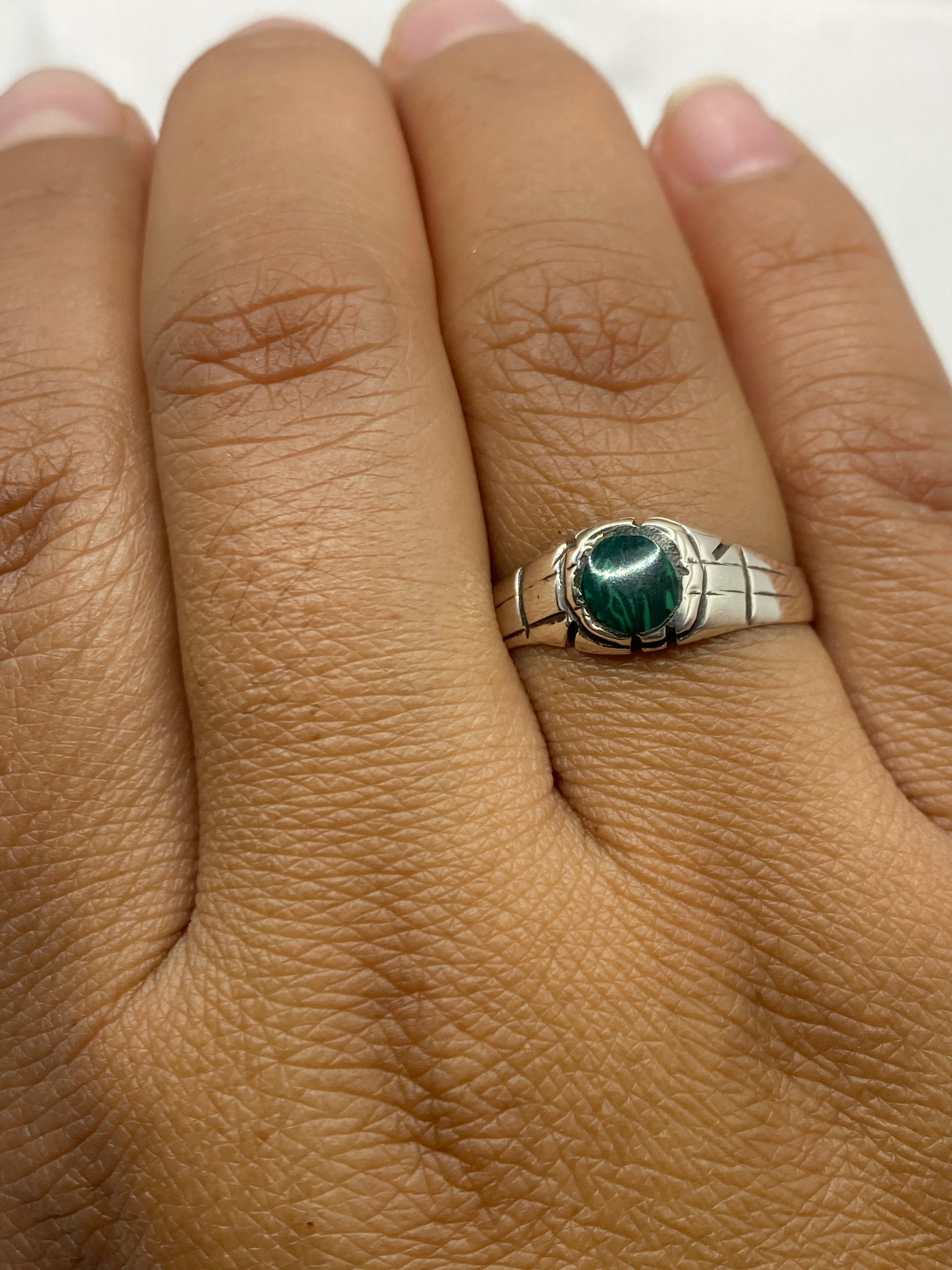 Anillo de malaquita puesto en mano, mostrando el tamaño y el color verde natural de la piedra