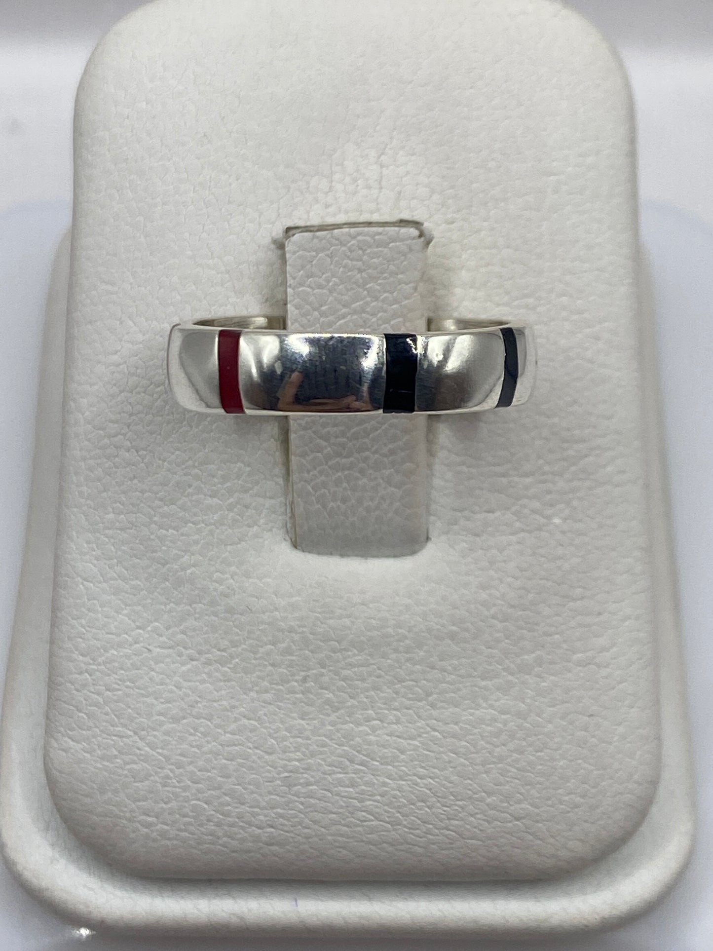 Anillo de plata con ónix negro en banda geométrica, sobre almohada blanca