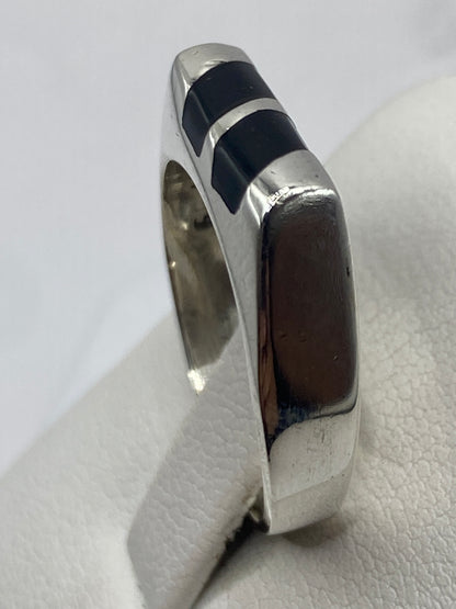 Anillo de ónix y plata puesto en dedo, mostrando el diseño geométrico frontal