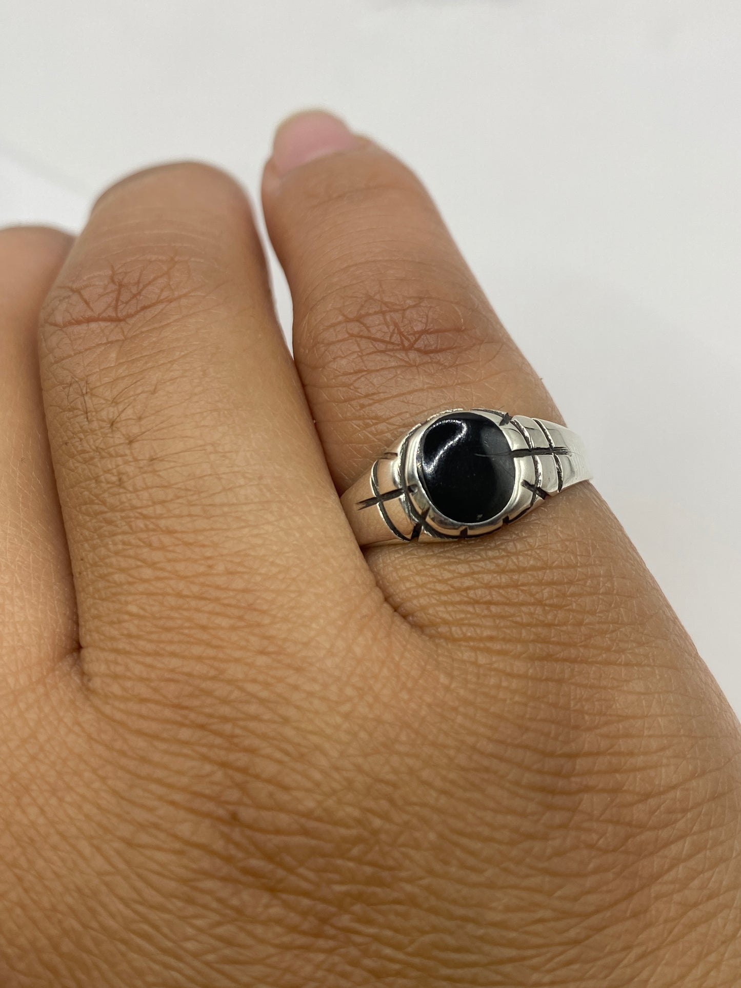 Anillo ónix en dedo mostrando el contraste entre piedra negra y metal plateado