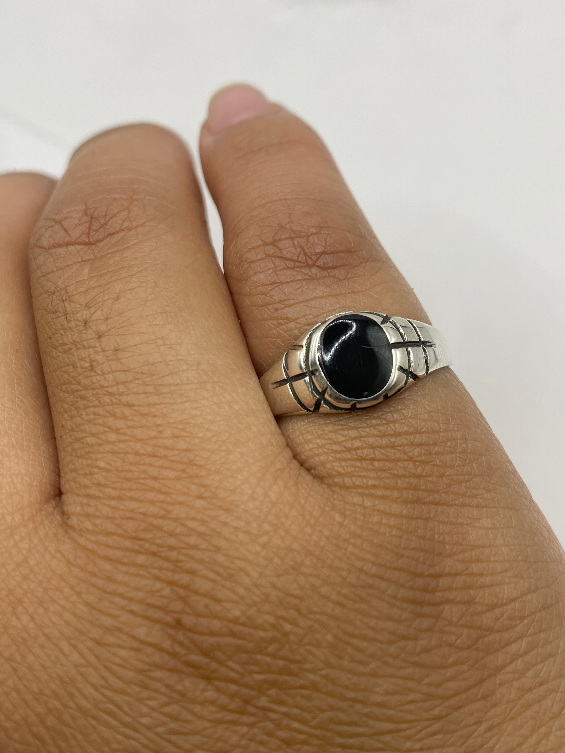 Anillo ónix en dedo mostrando el contraste entre piedra negra y metal plateado