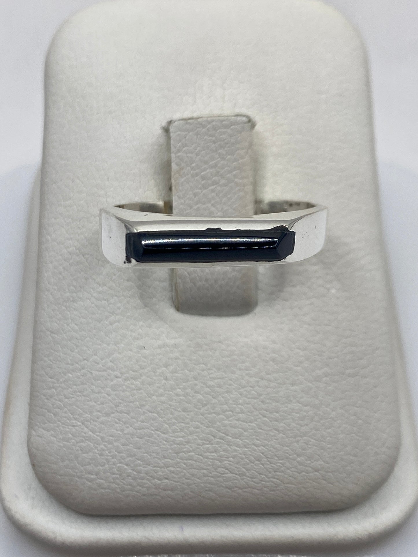 Anillo de plata con ónix negro pulido en mano de persona, diseño minimalista unisex