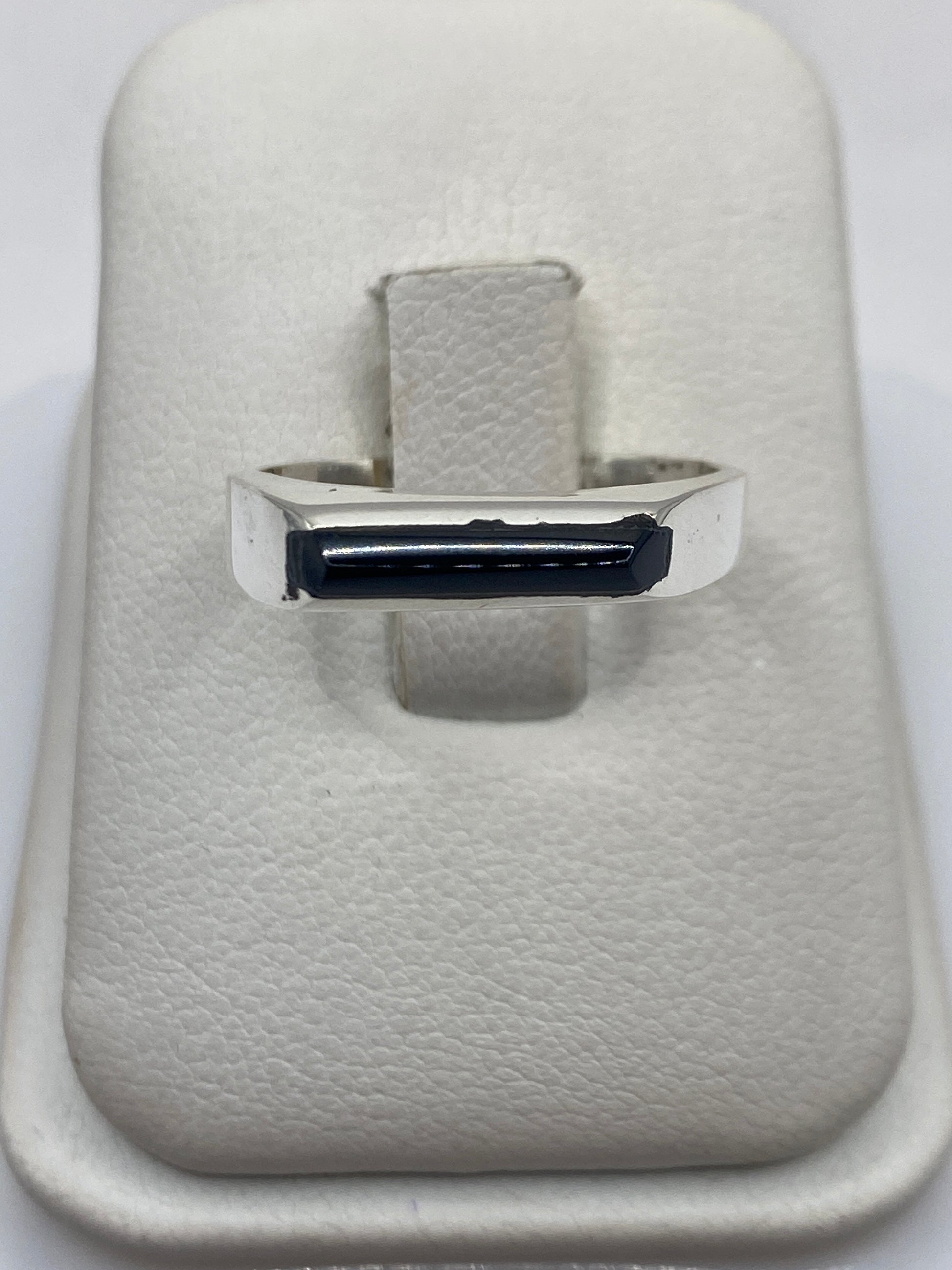 Anillo de plata con ónix negro pulido en mano de persona, diseño minimalista unisex