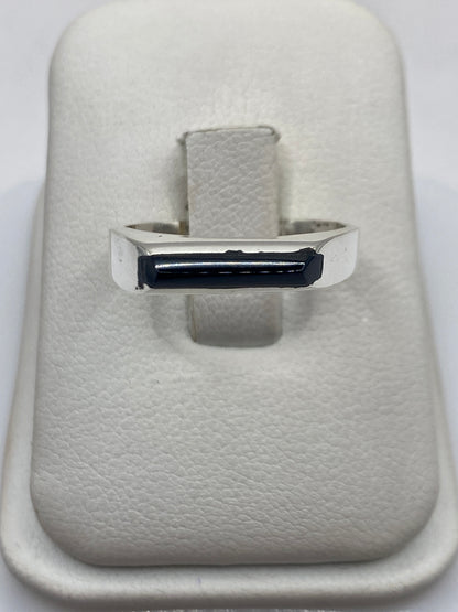 Anillo de plata con ónix negro pulido en mano de persona, diseño minimalista unisex