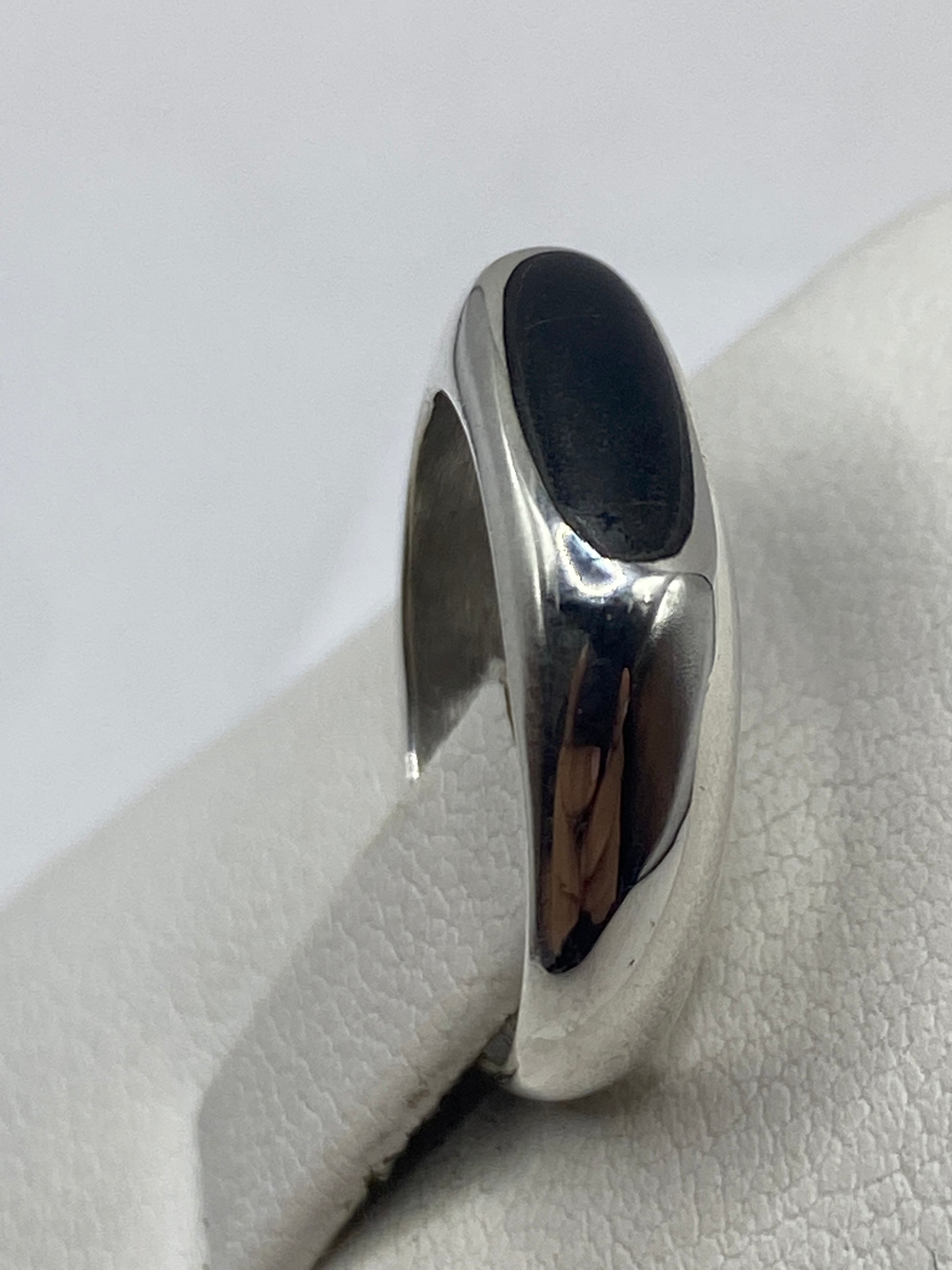 Detalle del ónix negro en plata, fotografía sobre mano con tono de piel medio