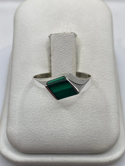 Anillo de plata minimalista con malaquita verde natural, vista frontal sobre soporte blanco