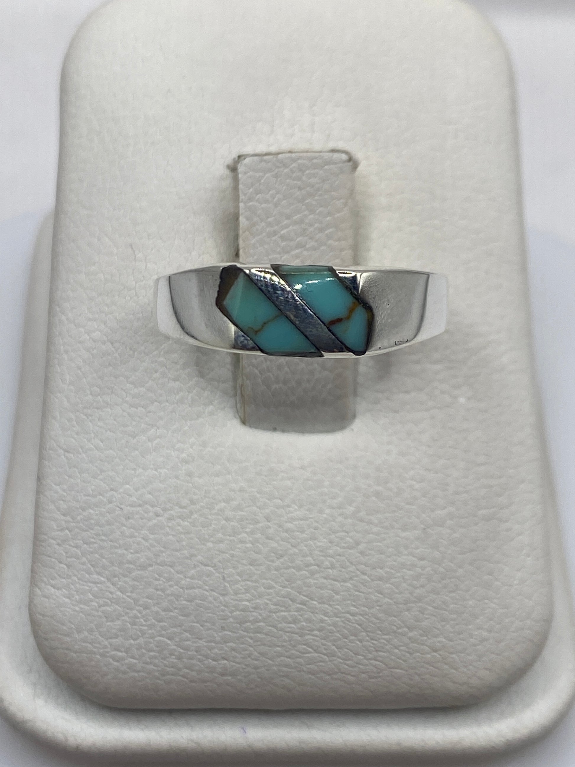Anillo de plata con turquesa azul engastada en diagonal, vista frontal sobre estuche blanco