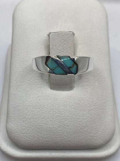 Anillo de plata con turquesa azul engastada en diagonal, vista frontal sobre estuche blanco