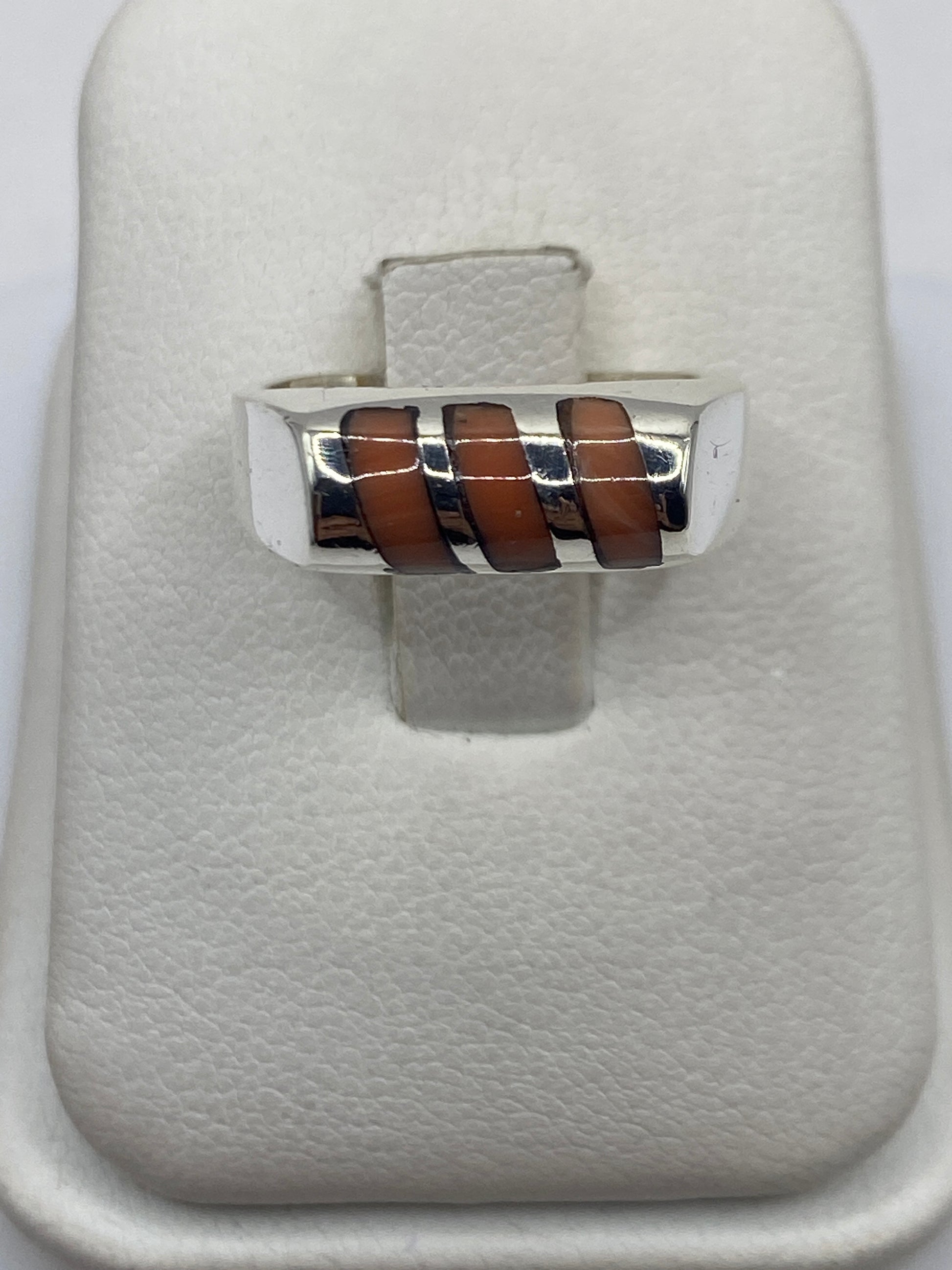 Anillo de plata con coral café cobrizo engastado en eslabones, vista frontal sobre dedo