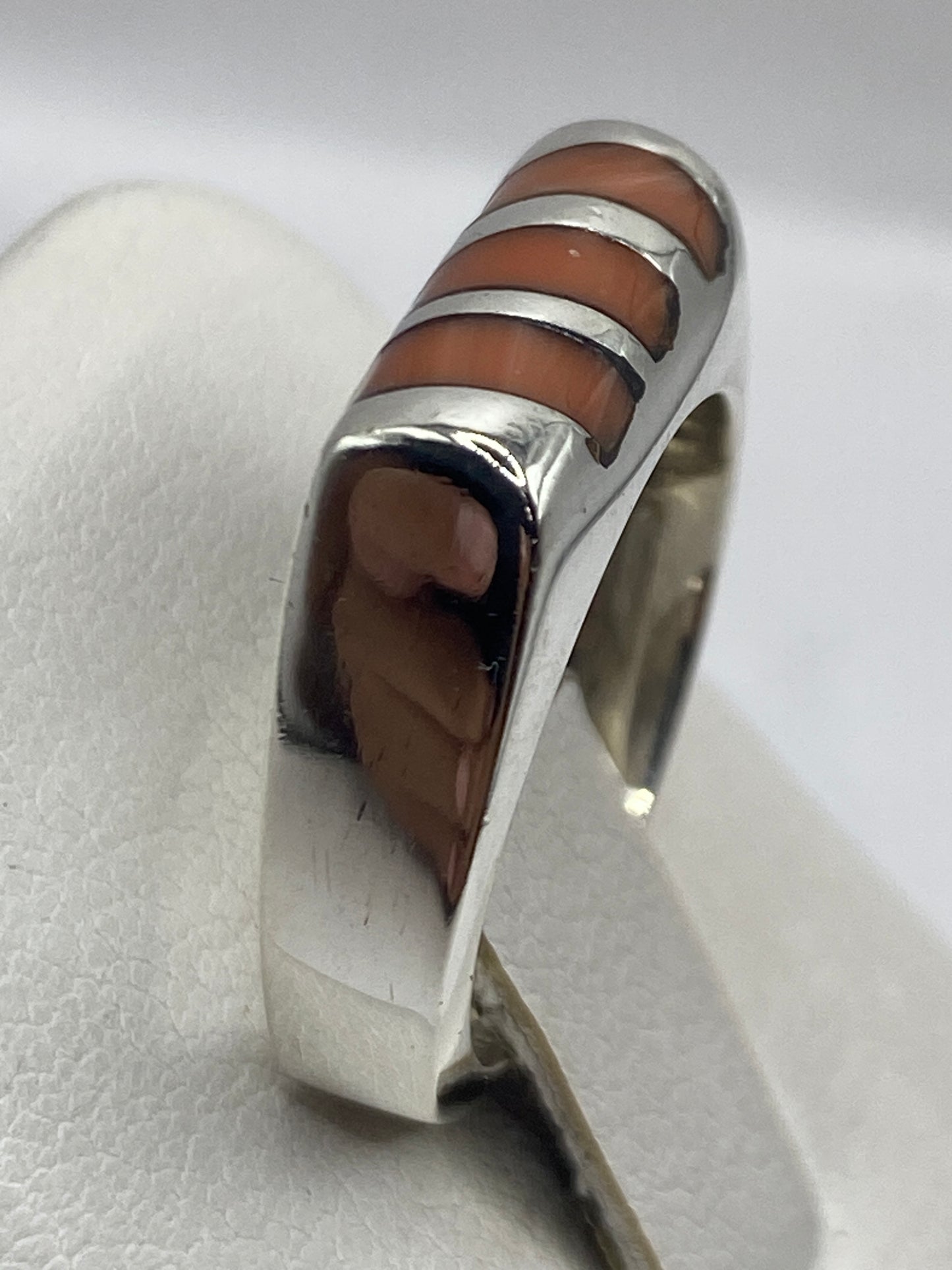 Anillo unisex de coral y plata en la mano mostrando peso y presencia