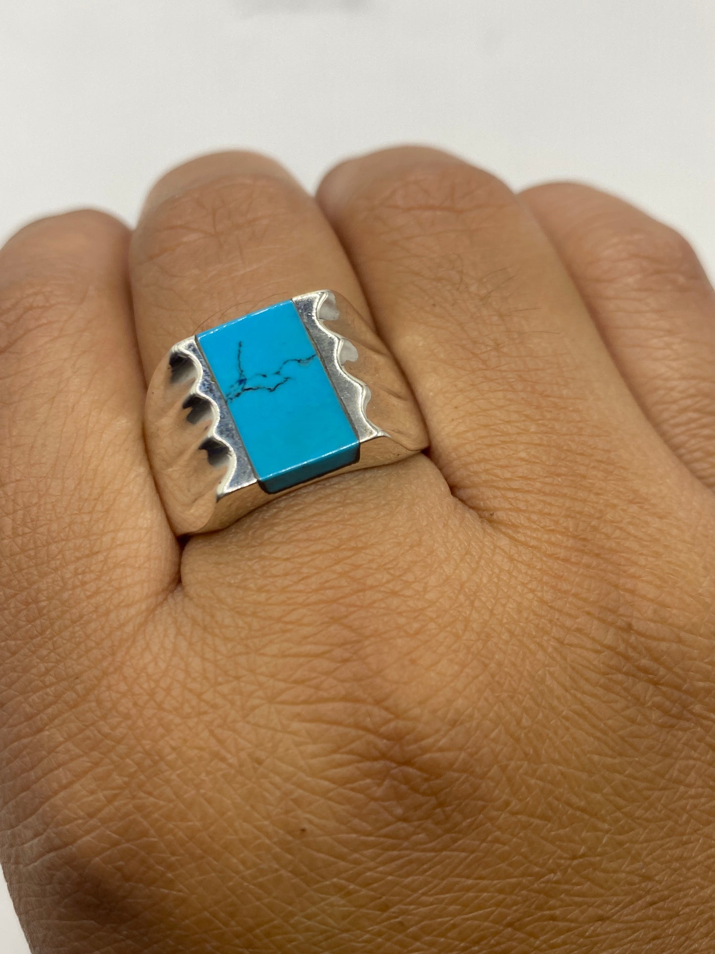 Anillo turquesa en mano masculina mostrando peso y presencia del sello .925