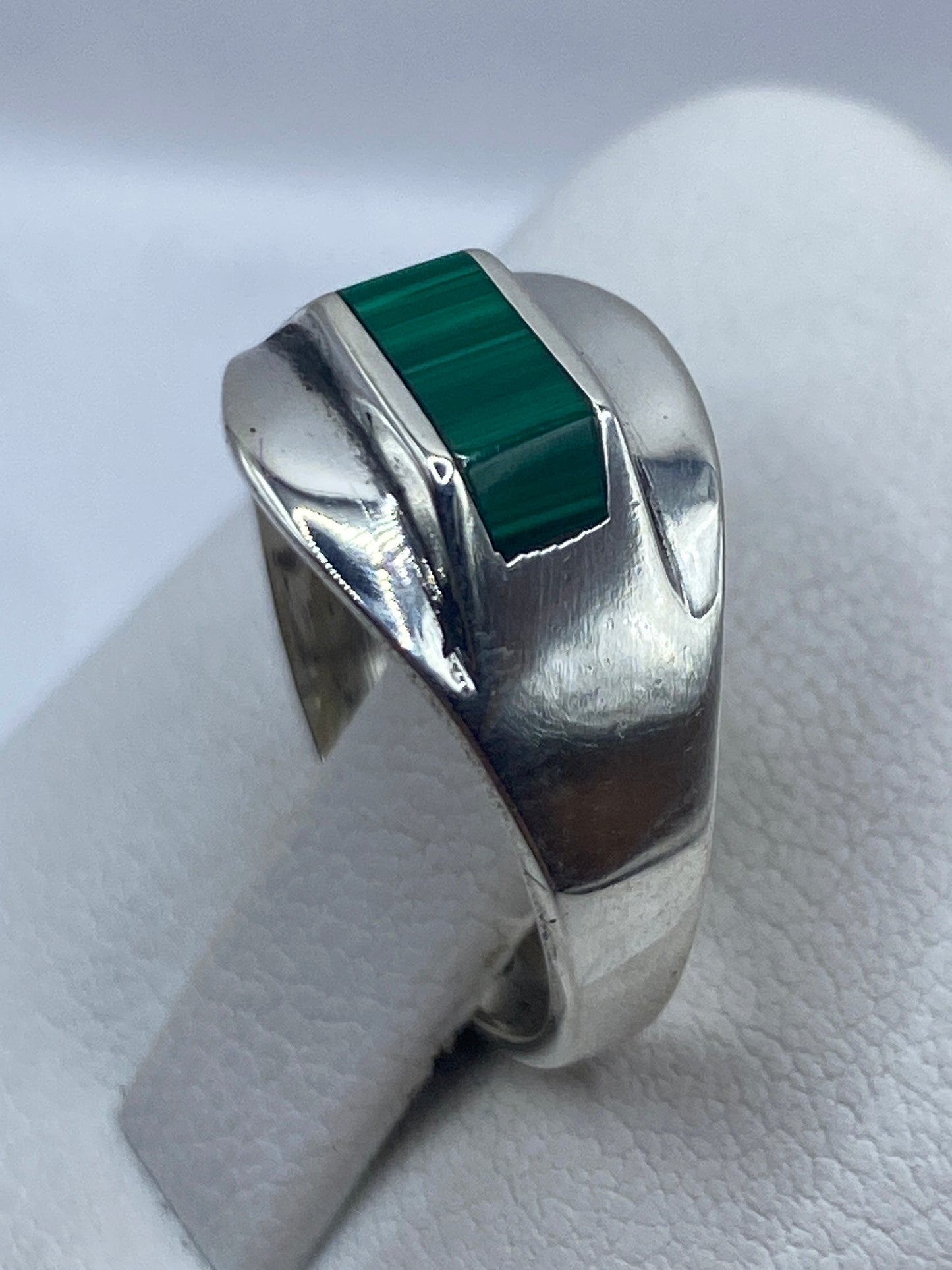 Anillo de malaquita puesto en dedo, mostrando el color verde y los patrones naturales
