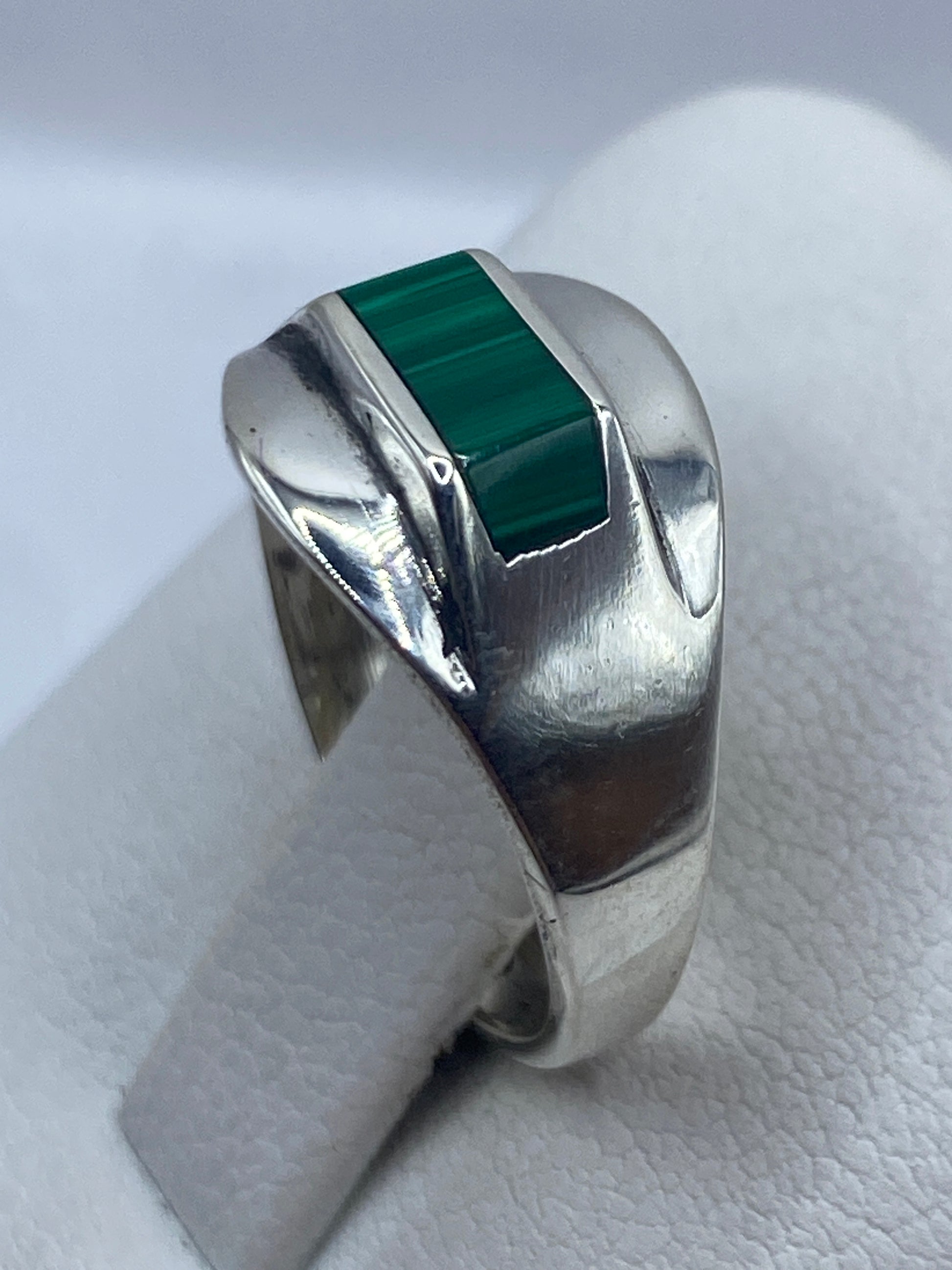 Anillo de malaquita puesto en dedo, mostrando el color verde y los patrones naturales