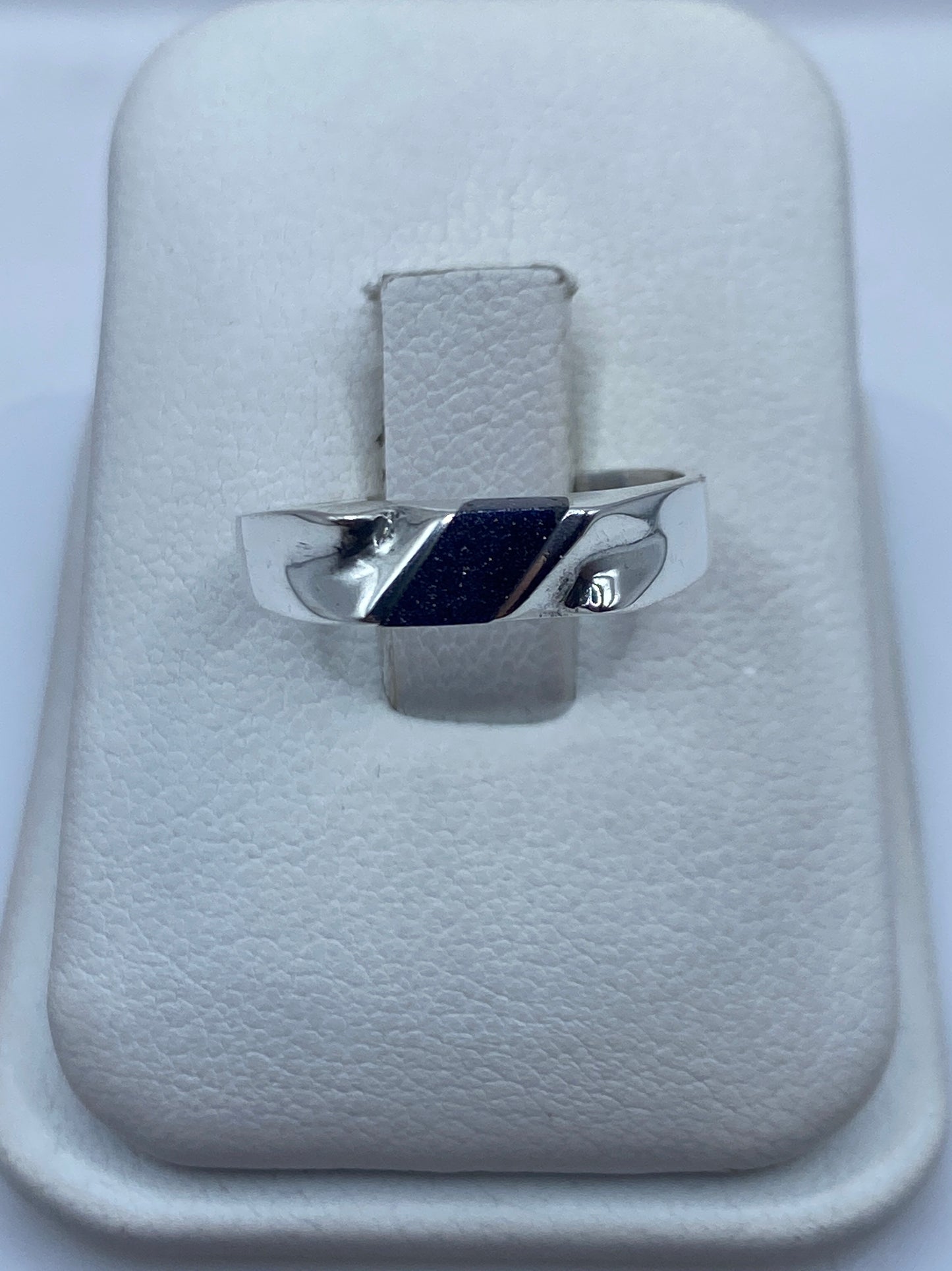 Anillo de plata .925 con piedra morada engastada, sobre cojín blanco