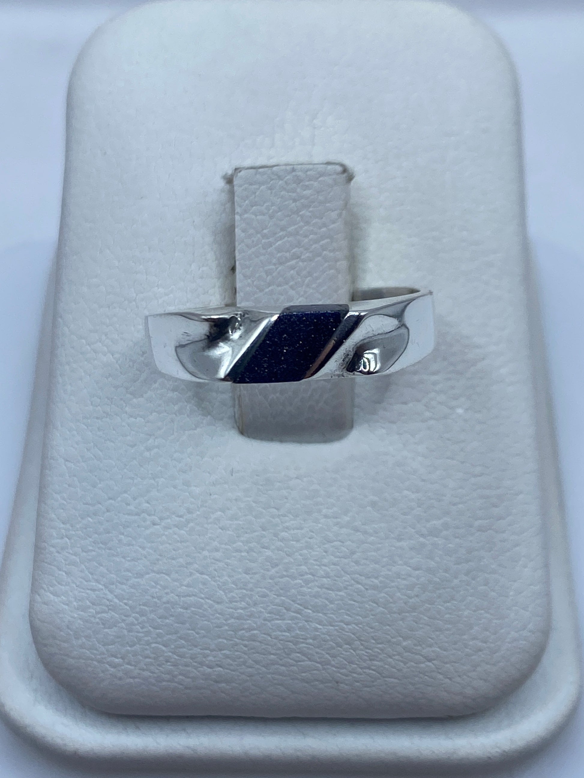 Anillo de plata .925 con piedra morada engastada, sobre cojín blanco