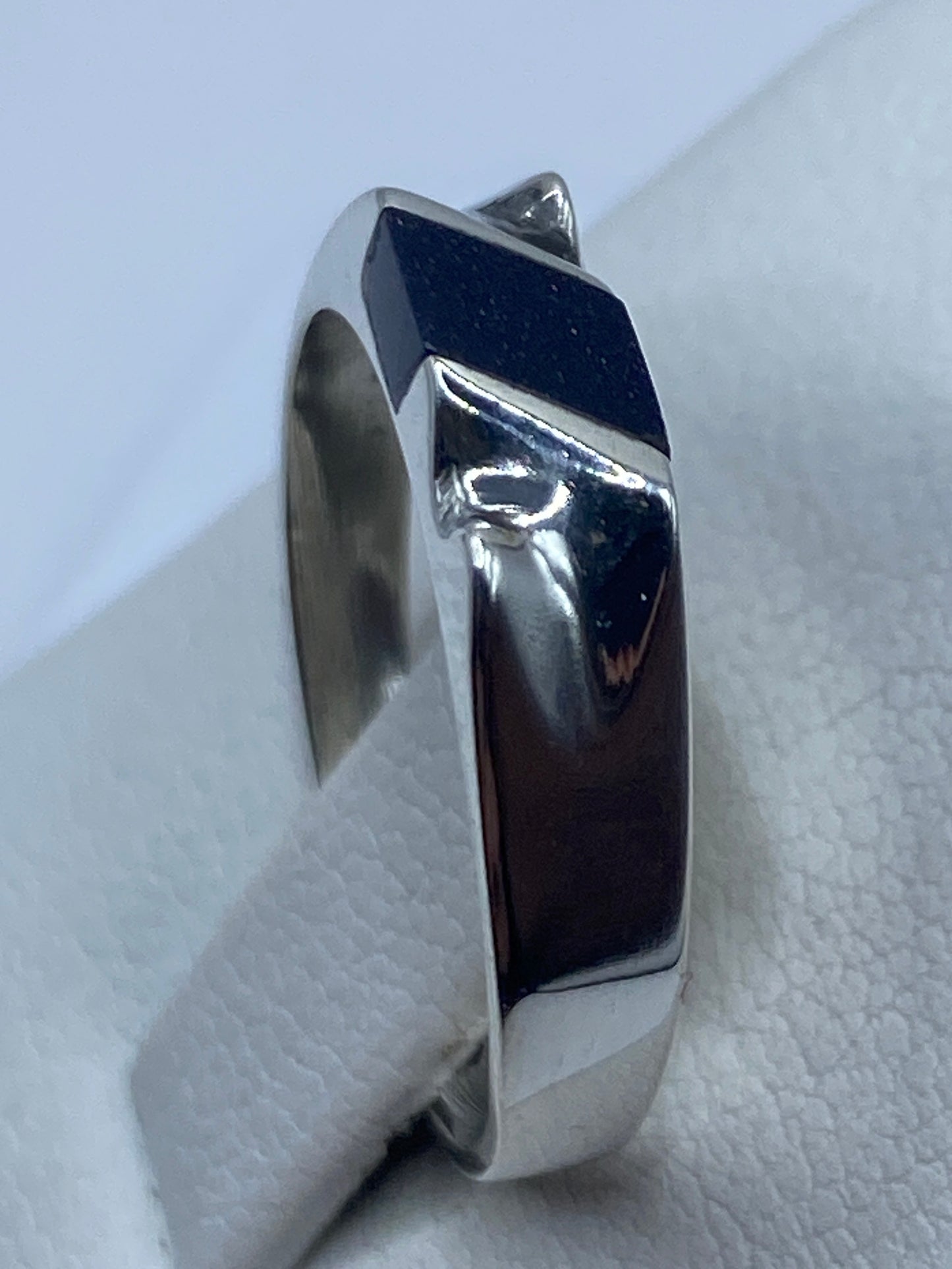 Anillo de plata puesto en dedo, mostrando la piedra morada y el pulido brillante