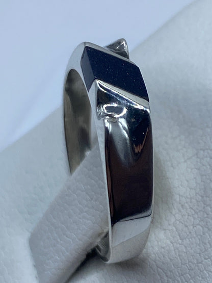 Anillo de plata puesto en dedo, mostrando la piedra morada y el pulido brillante