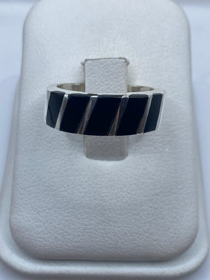 Anillo de plata con ónix negro en patrón geométrico sobre dedo índice