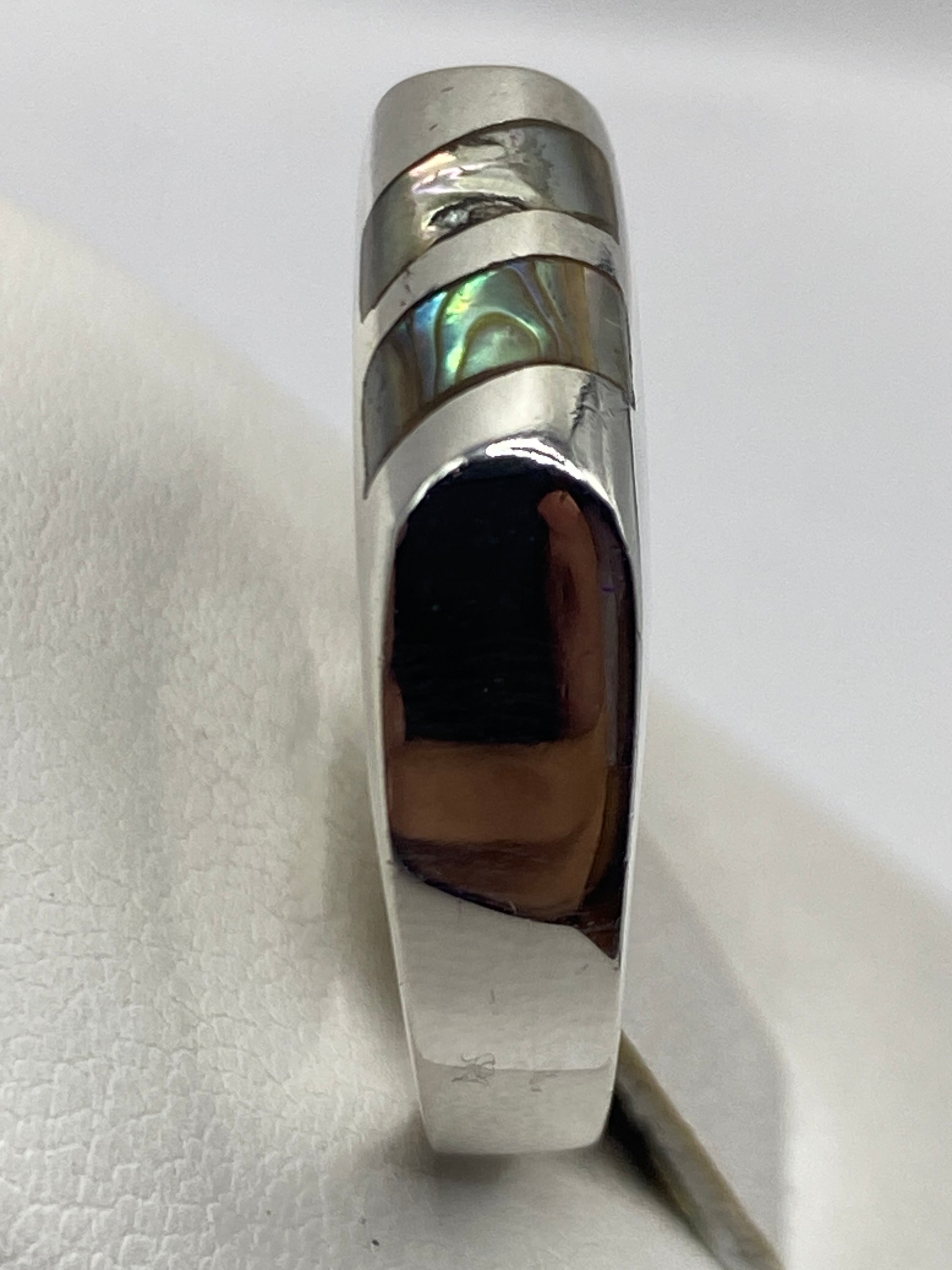 Detalle del anillo solitario con piedra capturando la luz, mostrando el pulido espejo de la plata
