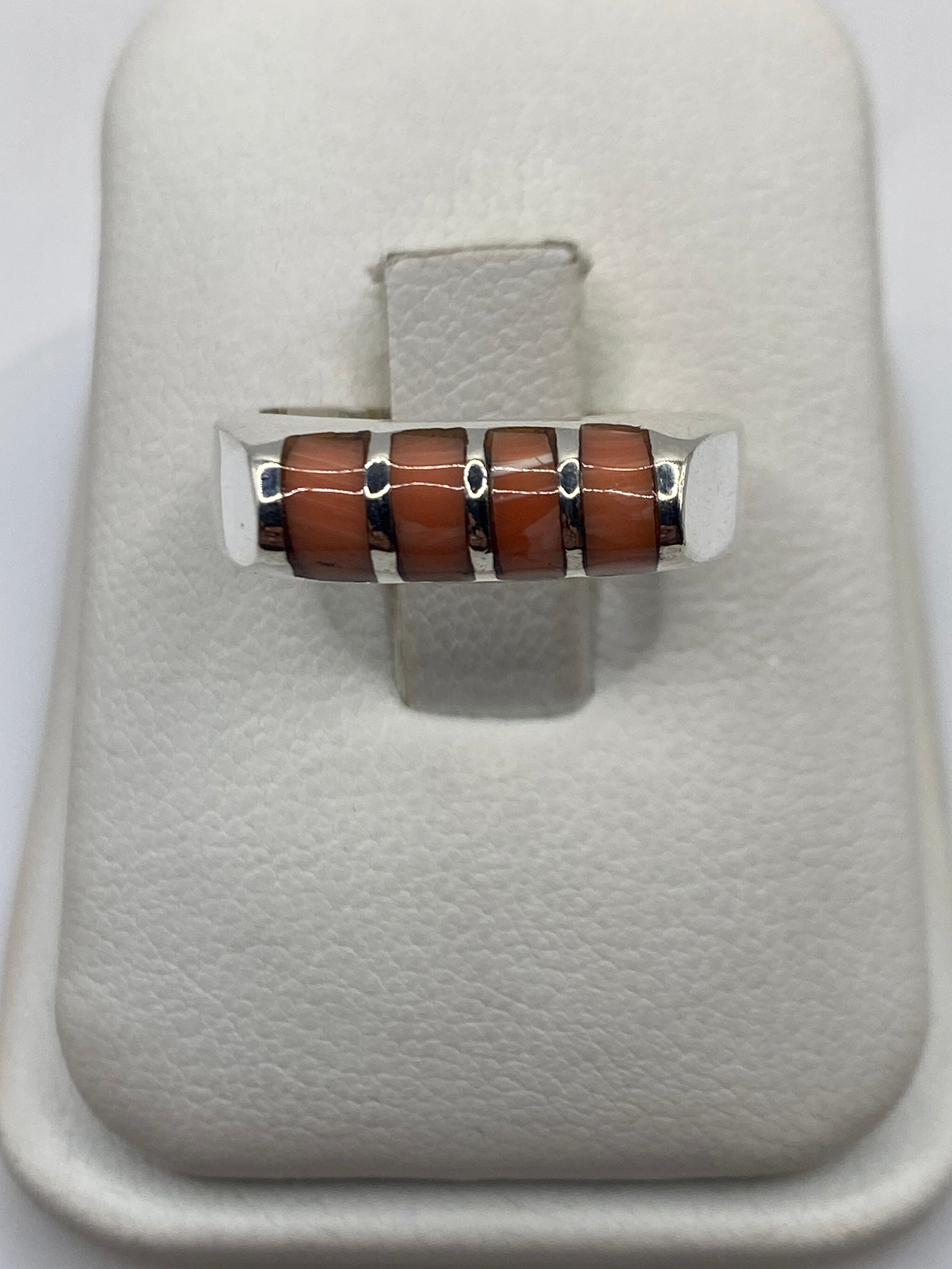 Anillo de plata con cuatro bloques de coral naranja en vista frontal sobre dedo