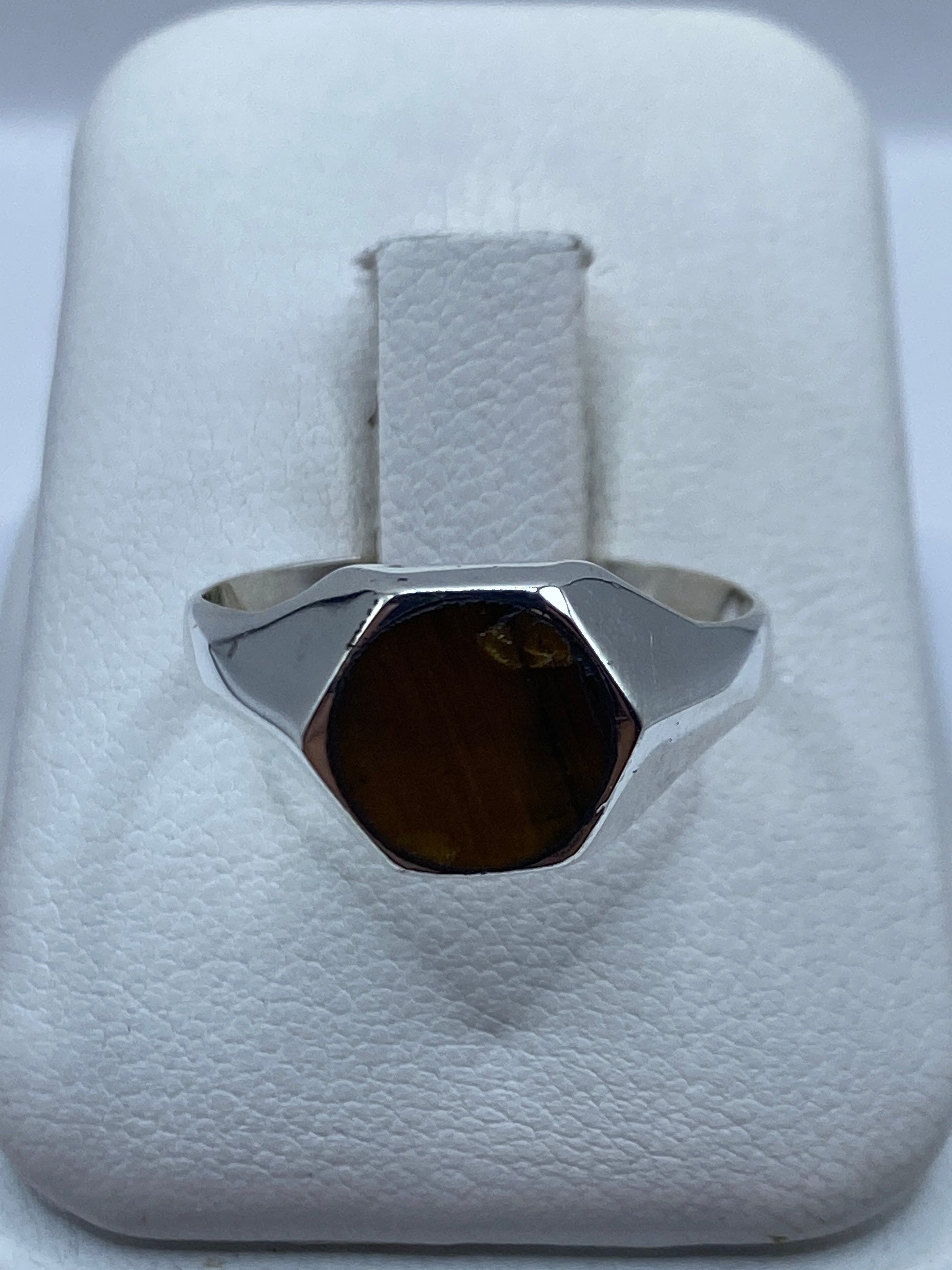 Anillo de plata con piedra natural café sobre presentador blanco