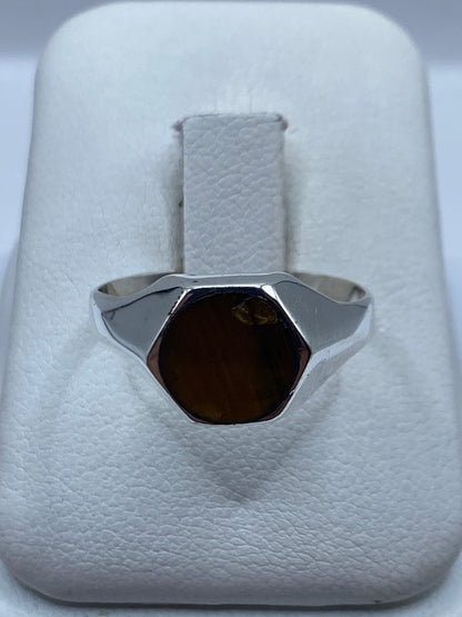 Anillo de plata con piedra natural café sobre presentador blanco