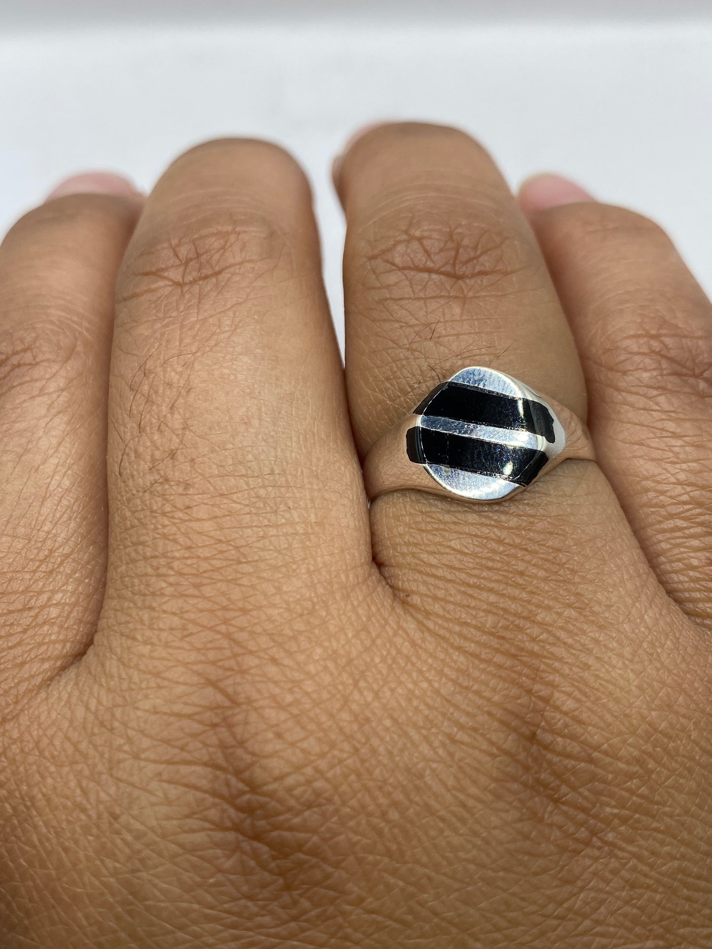 Anillo solitario ónix en dedo masculino, mostrando versatilidad unisex